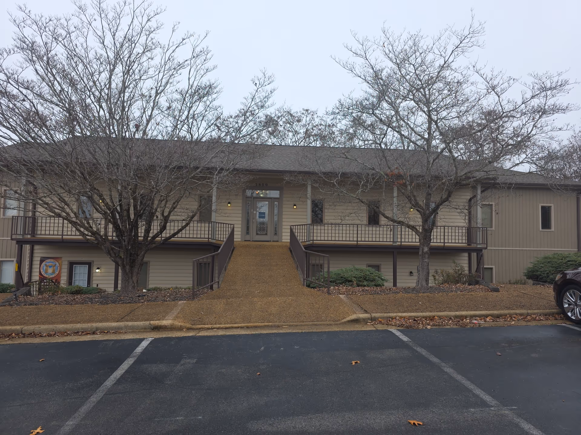 Exterior view of an AccentCare Home Health facility with stairs, railing, and leafless trees.