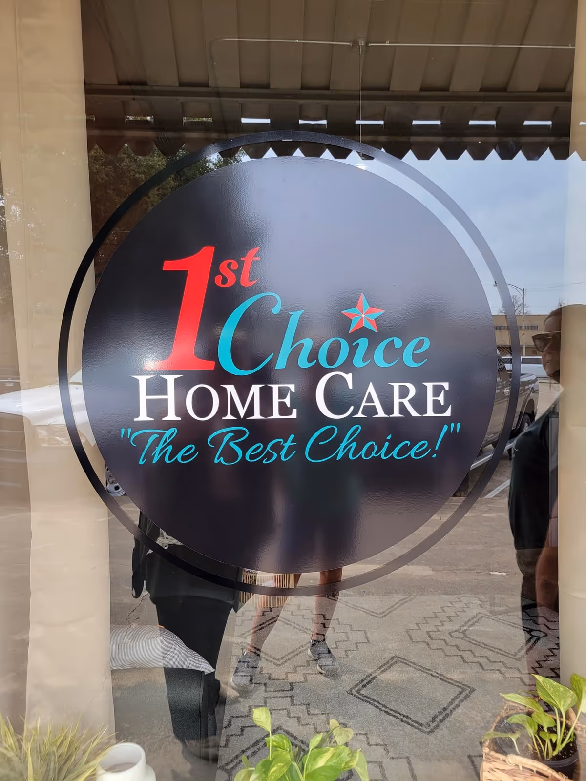 Circular sign for 1st Choice Home Care on a glass storefront window.