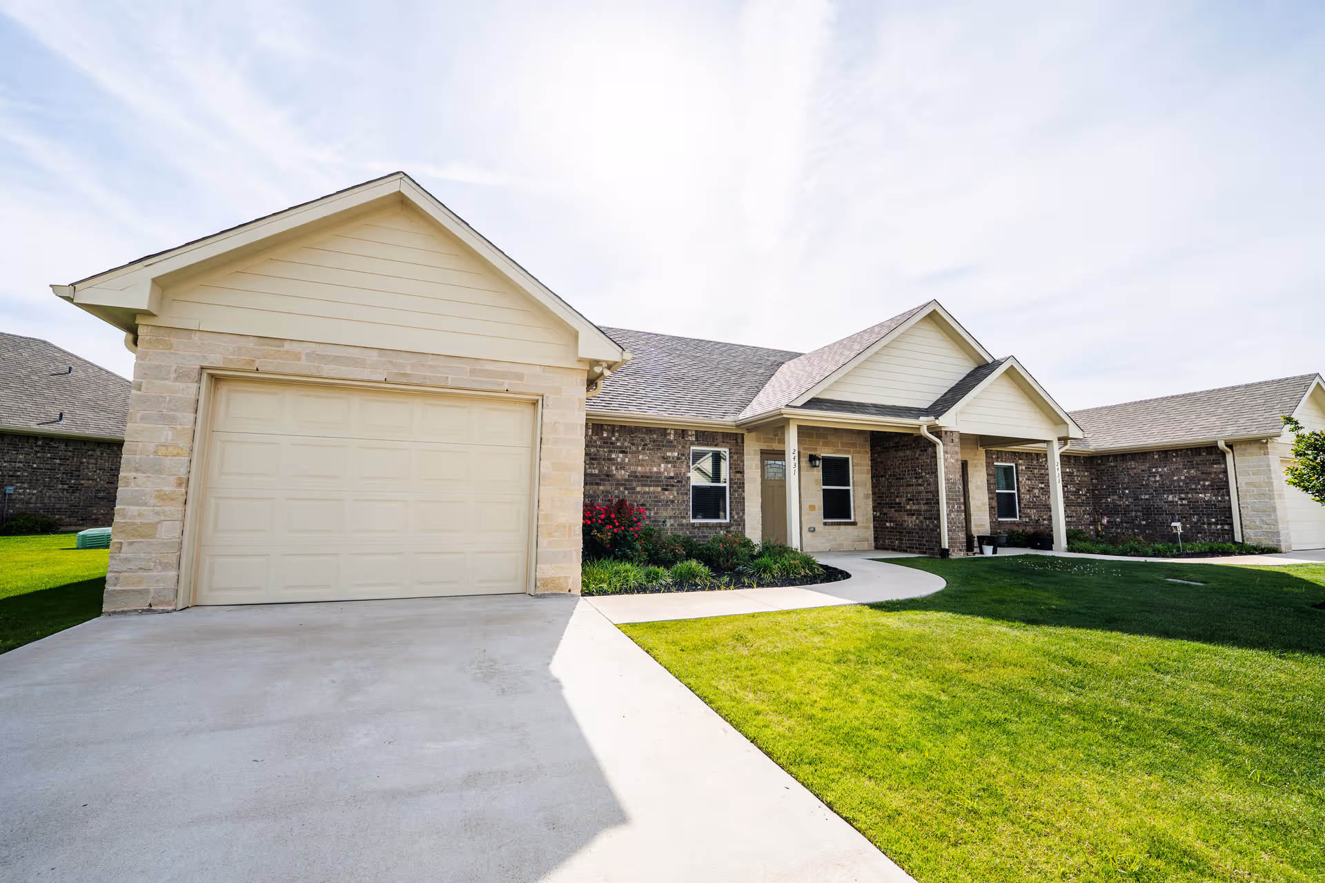 A single-story brick and stone residence with a garage, driveway, and well-kept lawn.