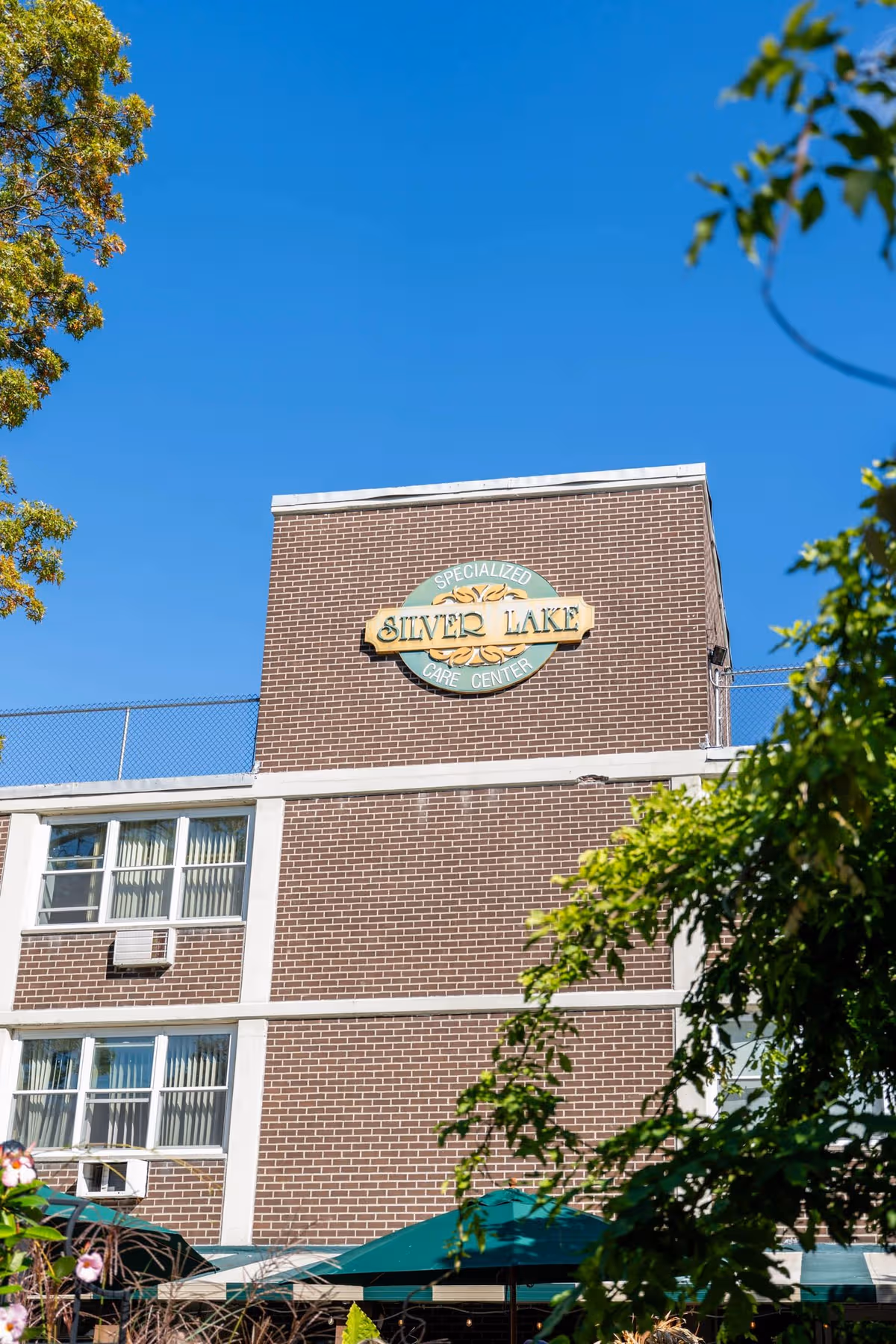 Brick exterior of Silver Lake Specialized Care Center with a circular sign and trees.