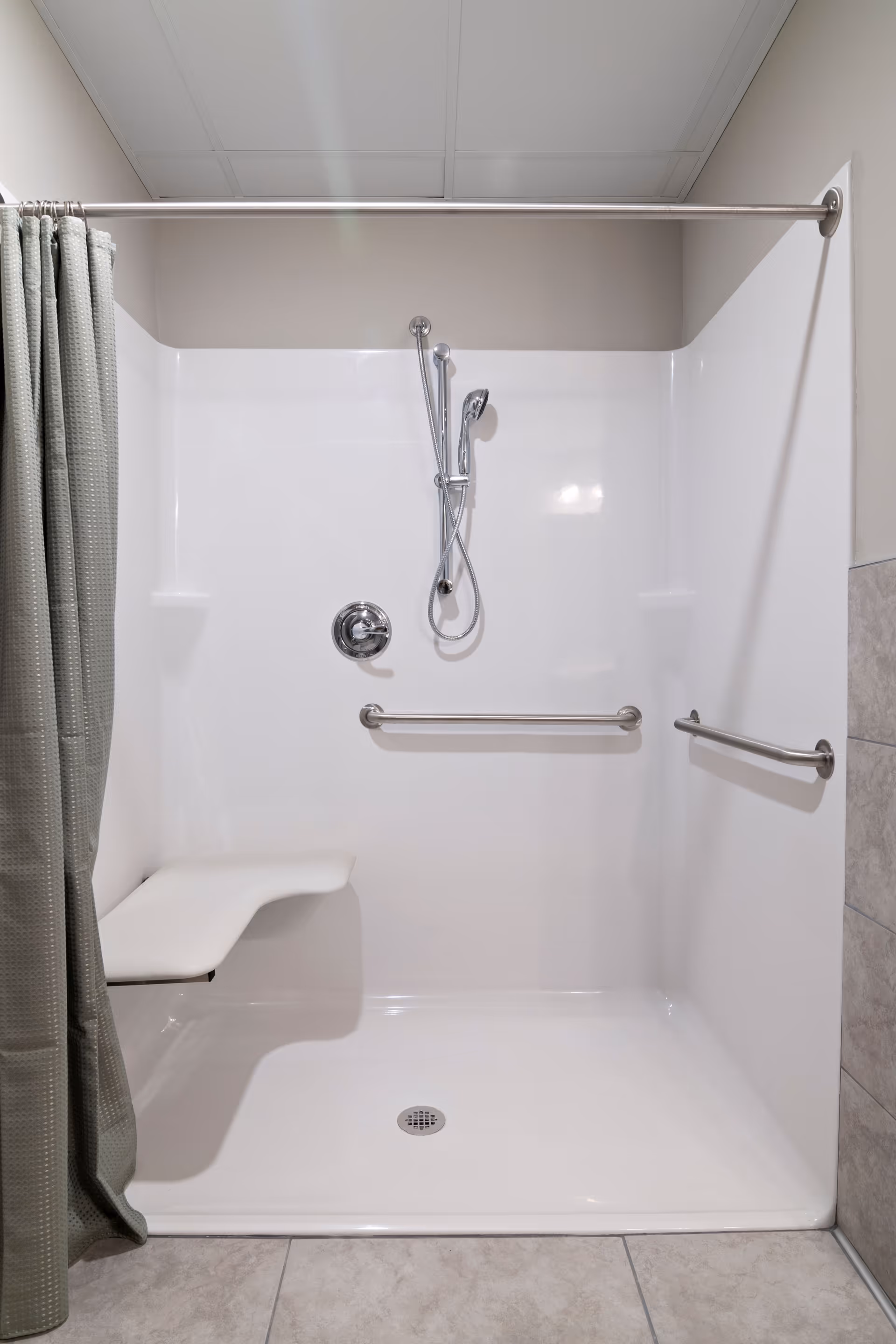 Accessible bathroom/shower with bench, grab bars, and handheld shower.