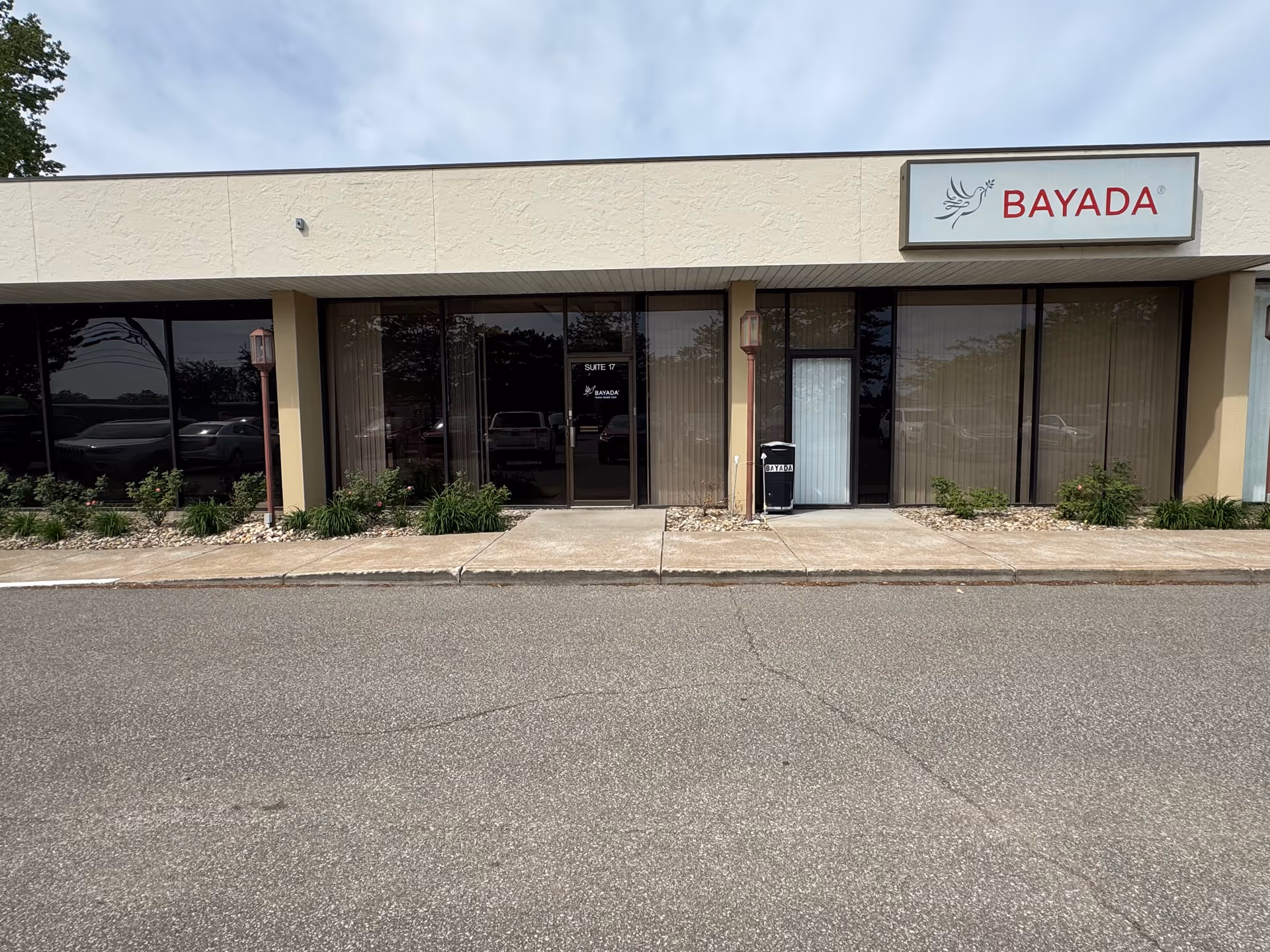 Front view of a beige commercial building with glass storefronts and a BAYADA sign.