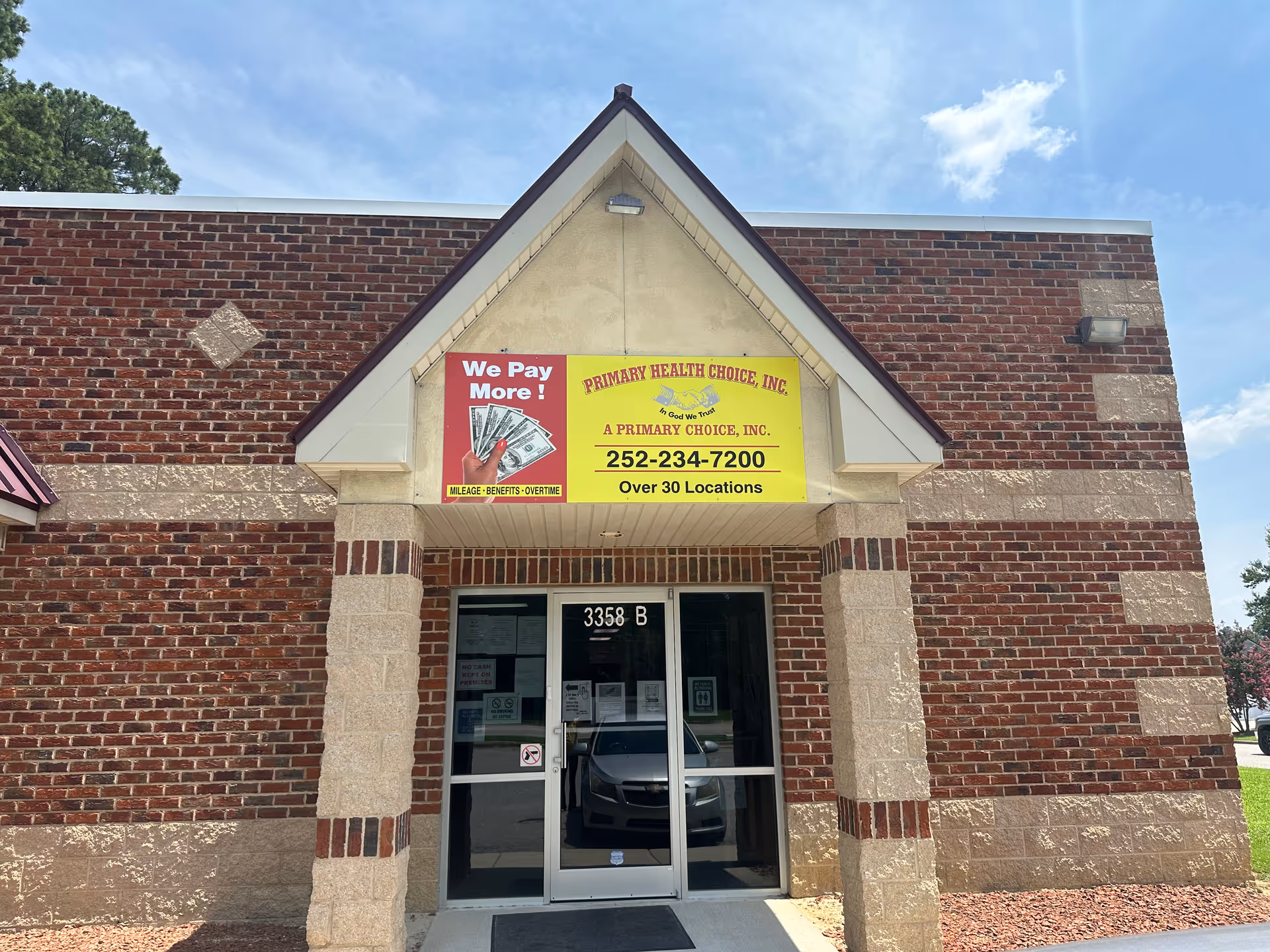 Brick building exterior with a yellow sign above glass doors at the entrance.