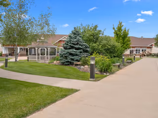 Facade of Neilson Place senior living facility with manicured lawn and trees.