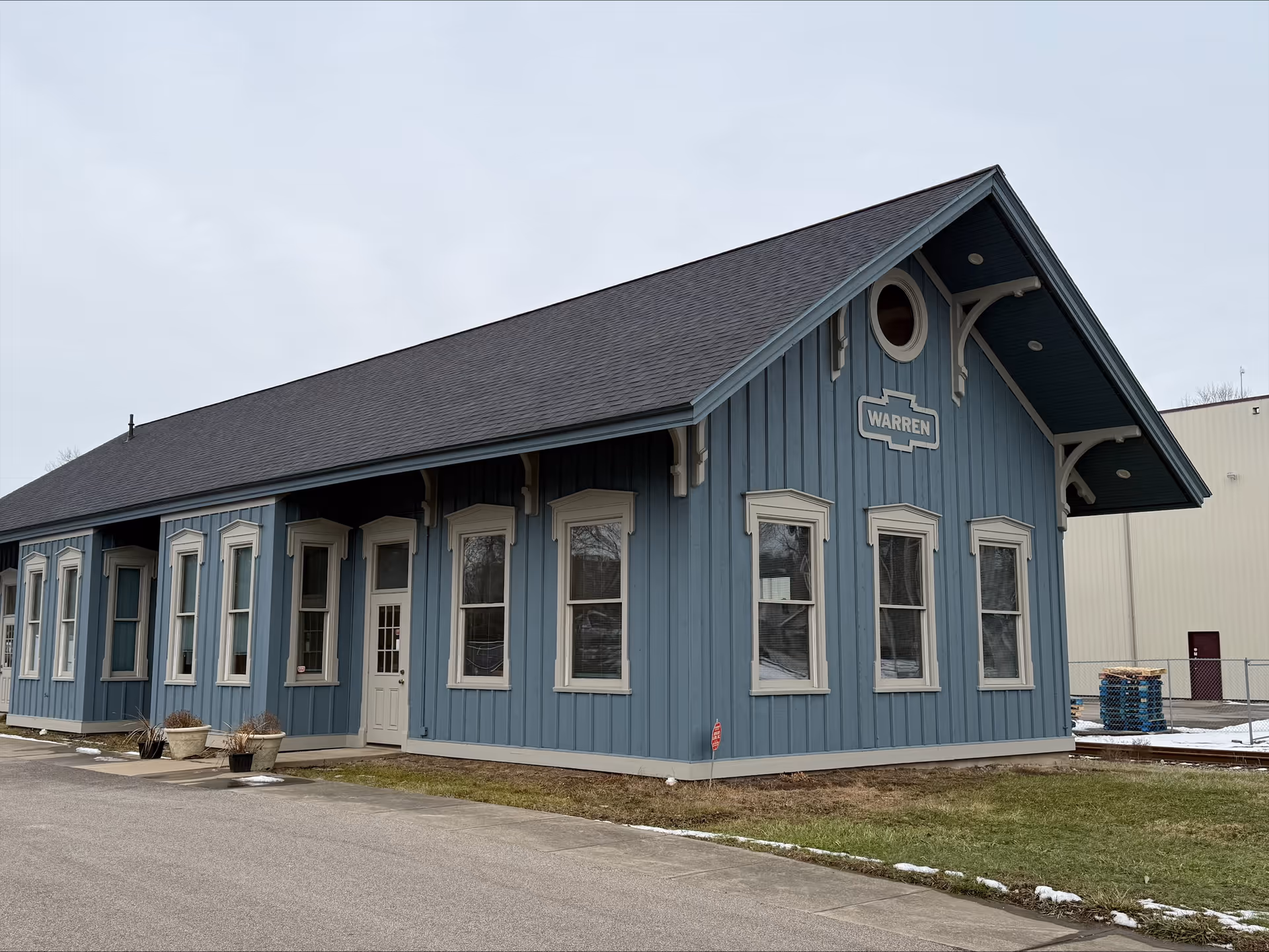 Blue wooden facility exterior with white-trimmed windows and peaked roof, front view.