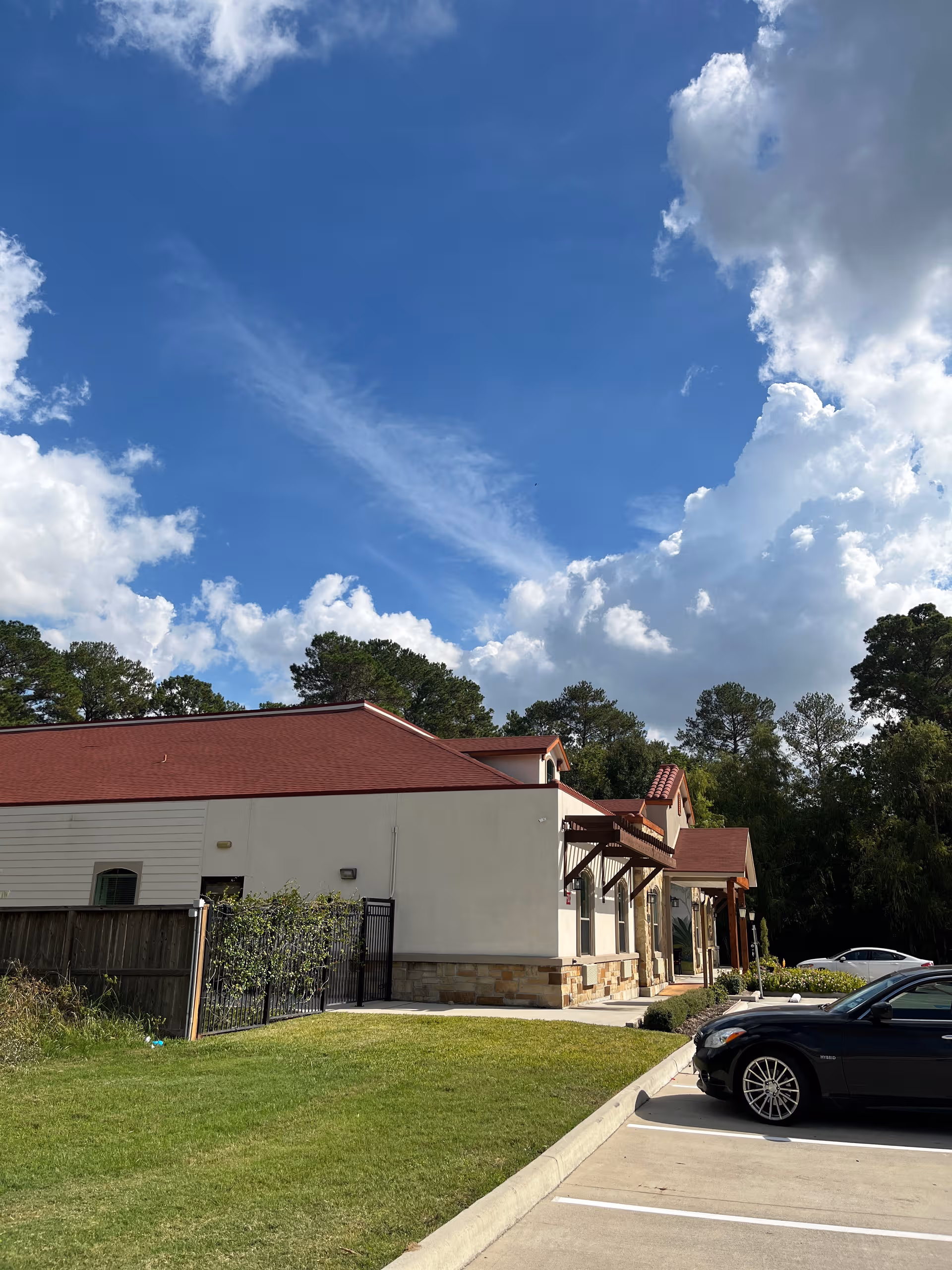 Exterior view of Village Green Cypress Louetta building with parked cars and blue sky