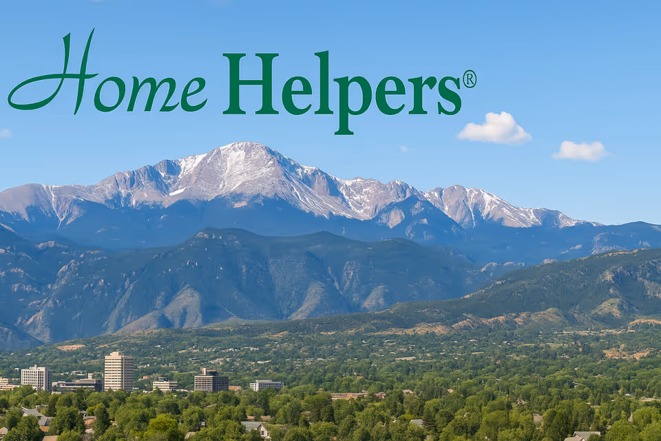 Large green Home Helpers sign above mountains and city skyline.