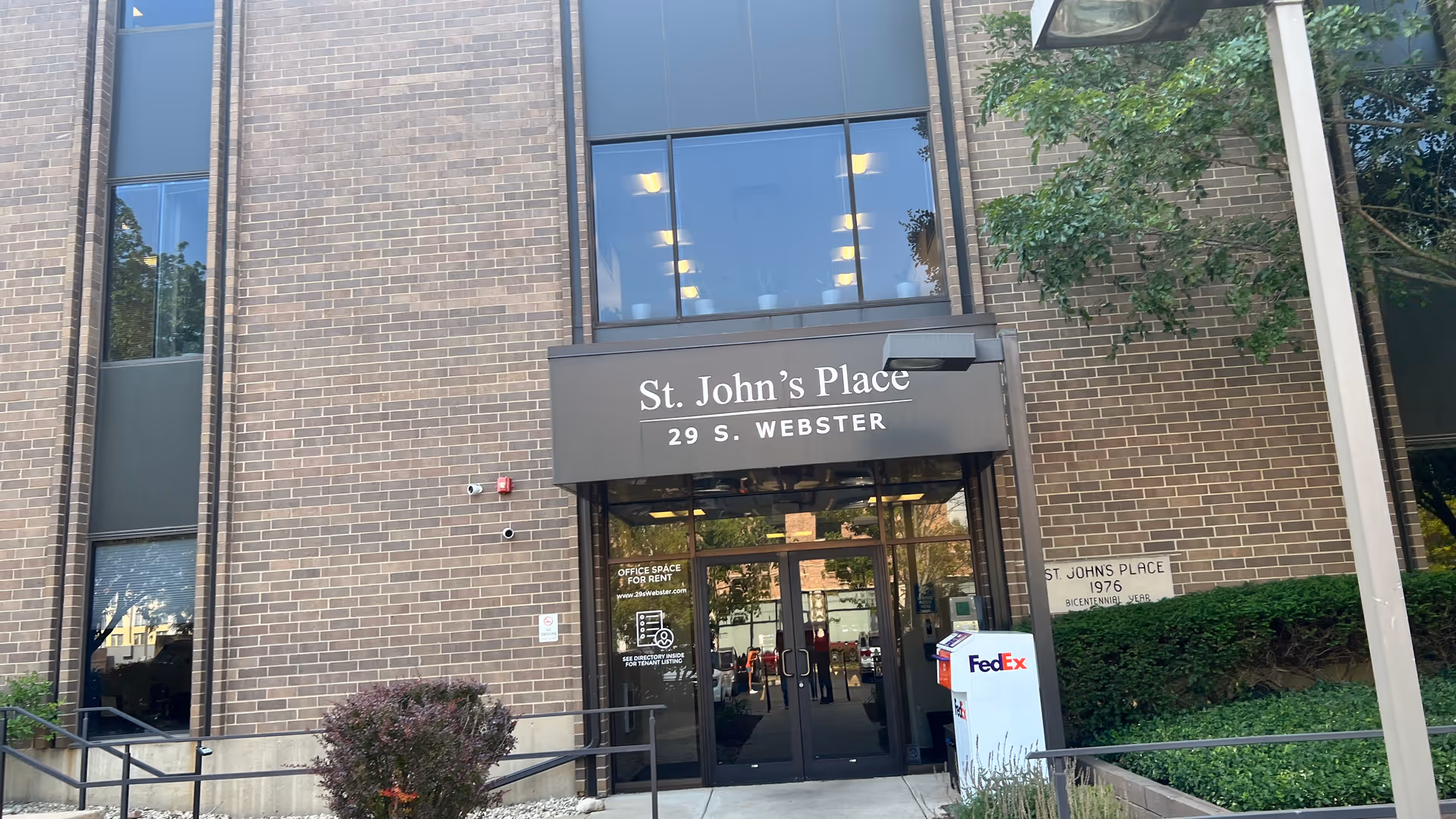Front entrance of St. John's Place building with brick exterior and glass doors.