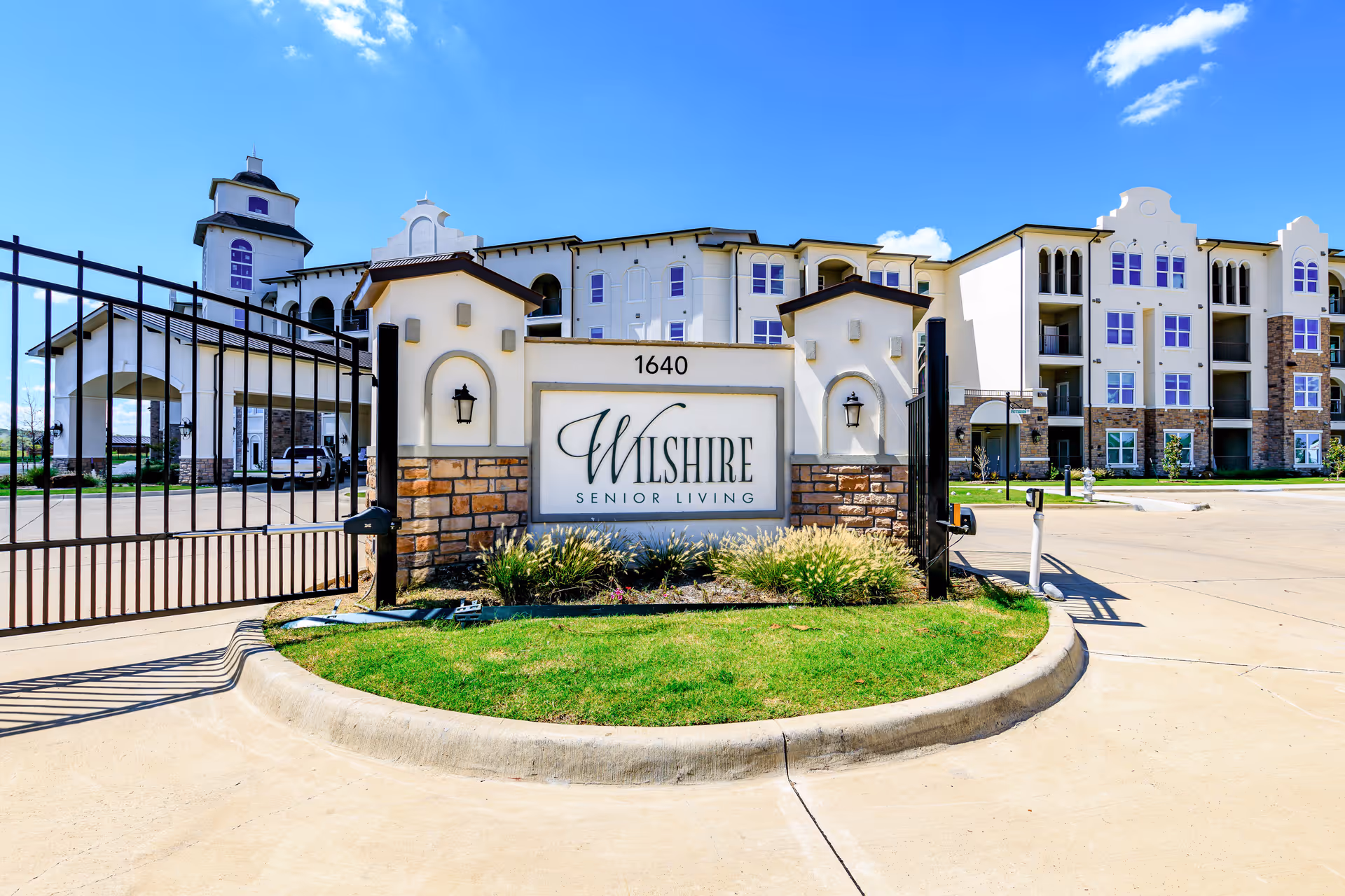 Gated entrance to Wilshire Senior Living with a sign and a modern building.