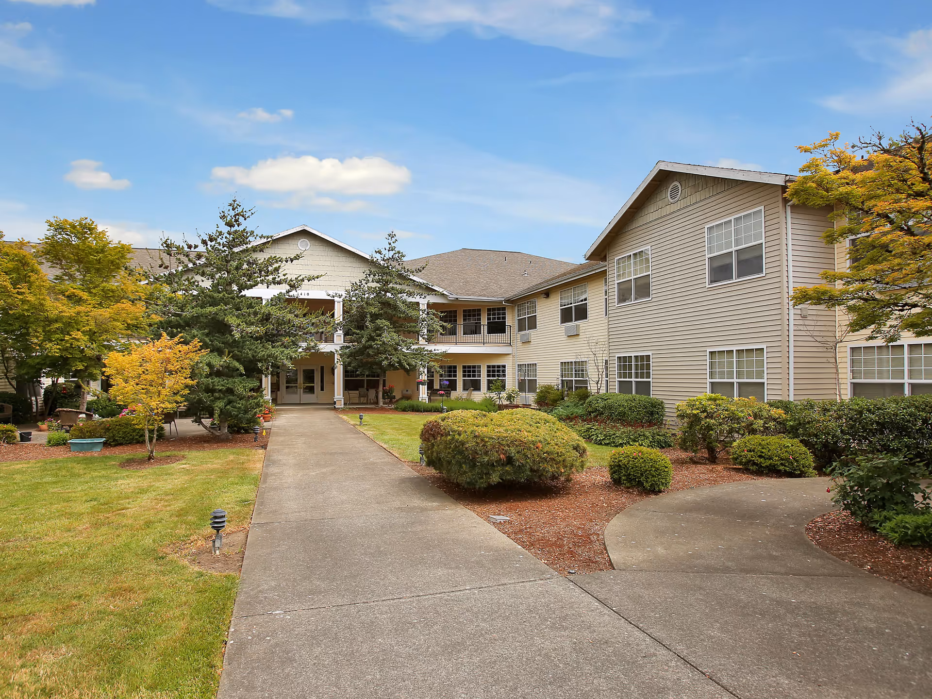Exterior view of Prestige Senior Living Huntington Terrace, with a paved walkway and manicured landscaping.
