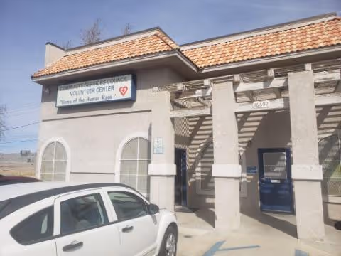 Front view of a beige building with a Volunteer Center sign and a parked car.
