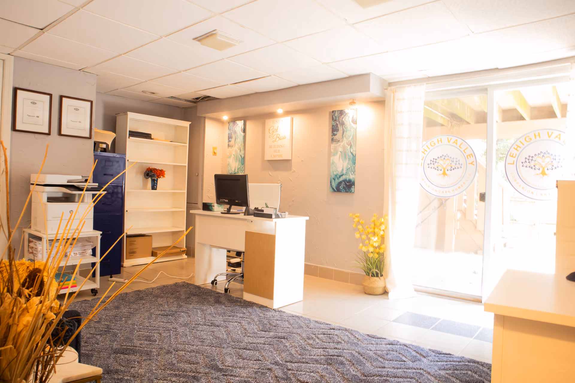 Reception area featuring a white desk, printer, shelves, and glass doors with Lehigh Valley logos.