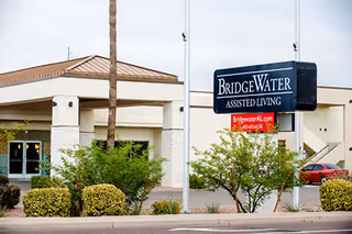 Exterior view of BridgeWater Assisted Living facility with sign and landscaped entrance.
