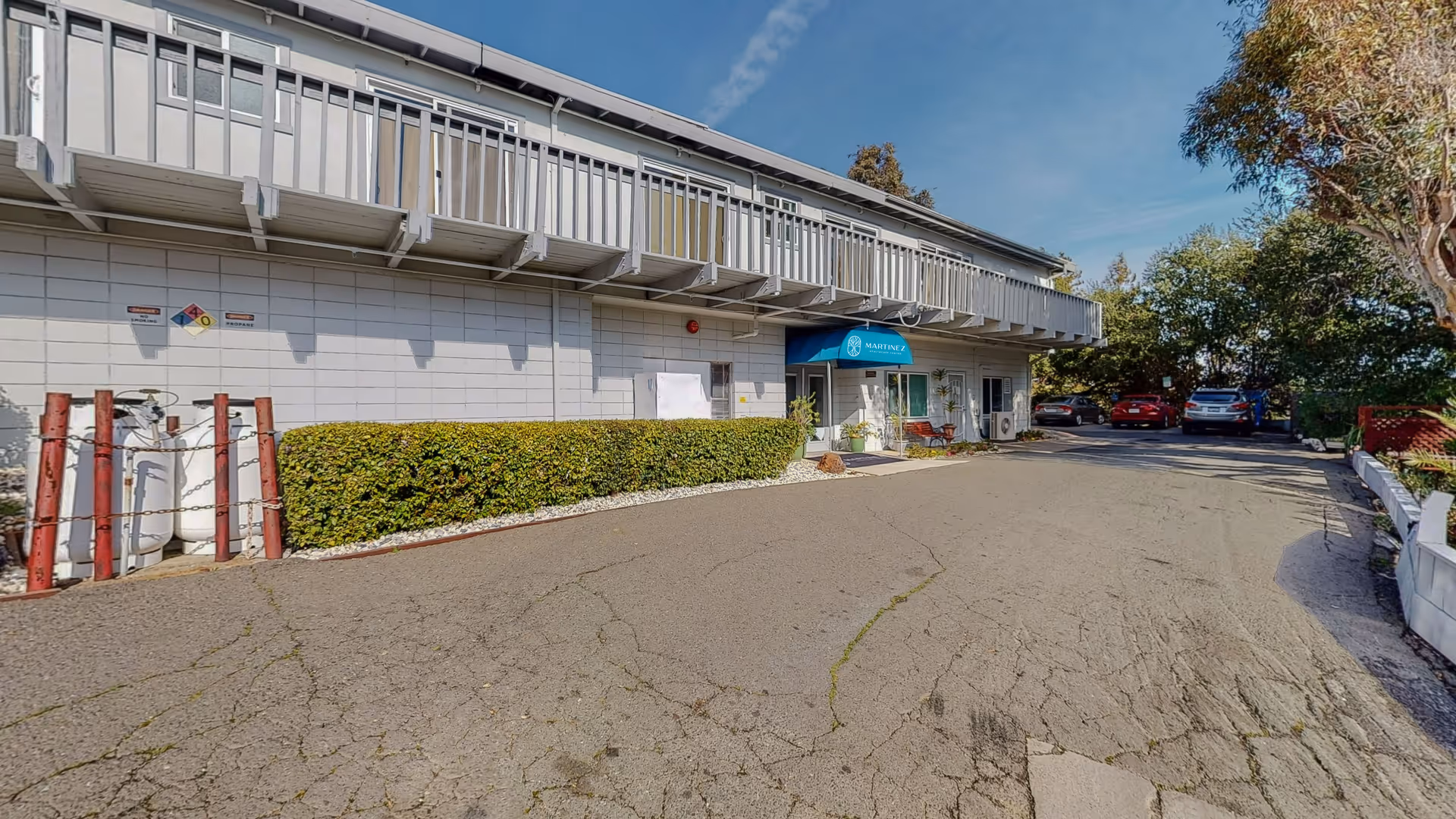 Exterior view of Martinez Healthcare Center with entrance, blue canopy, parking, and surrounding greenery.