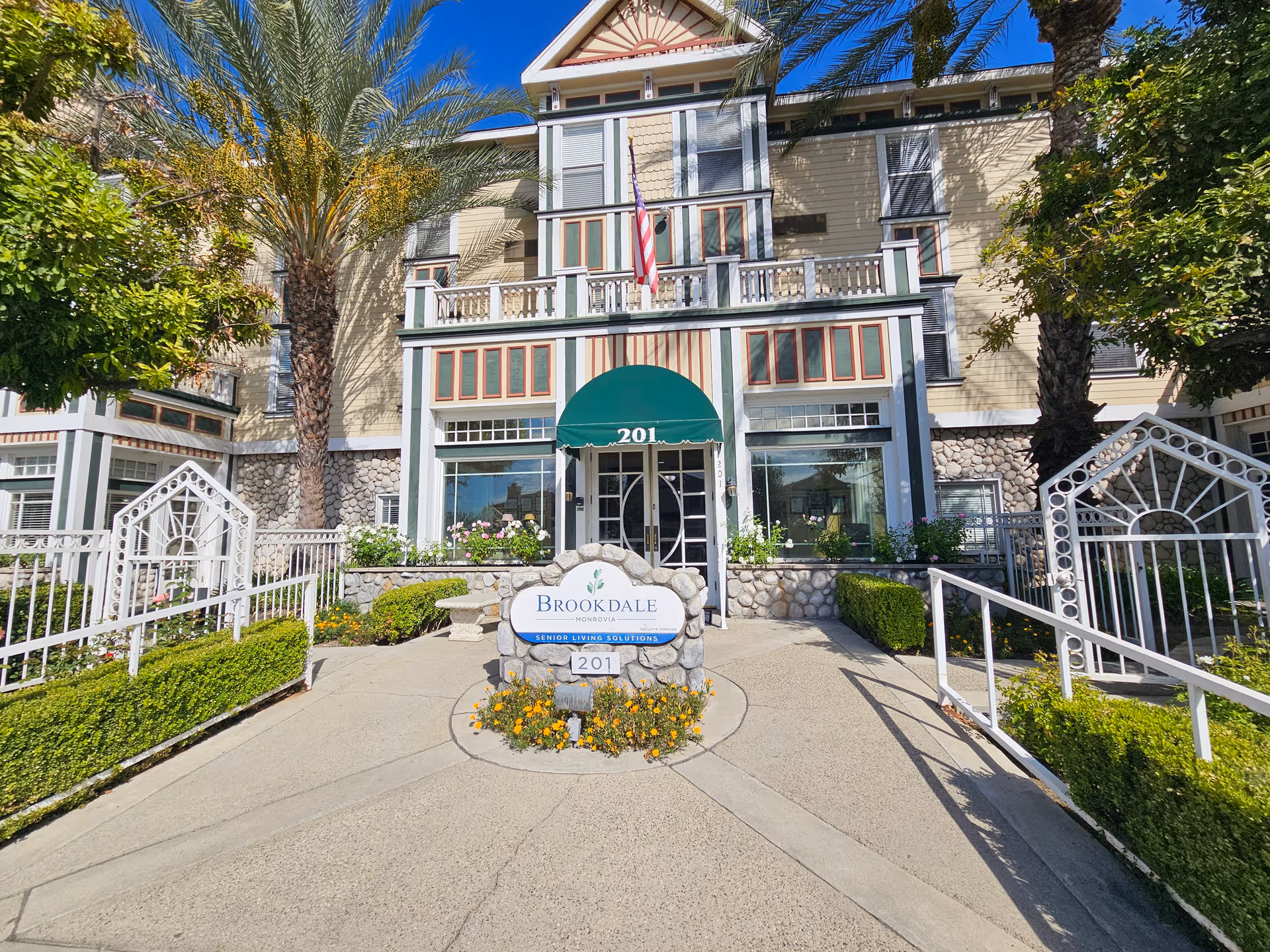 Exterior view of Brookdale Monrovia entrance with green awning and stone landscaping.