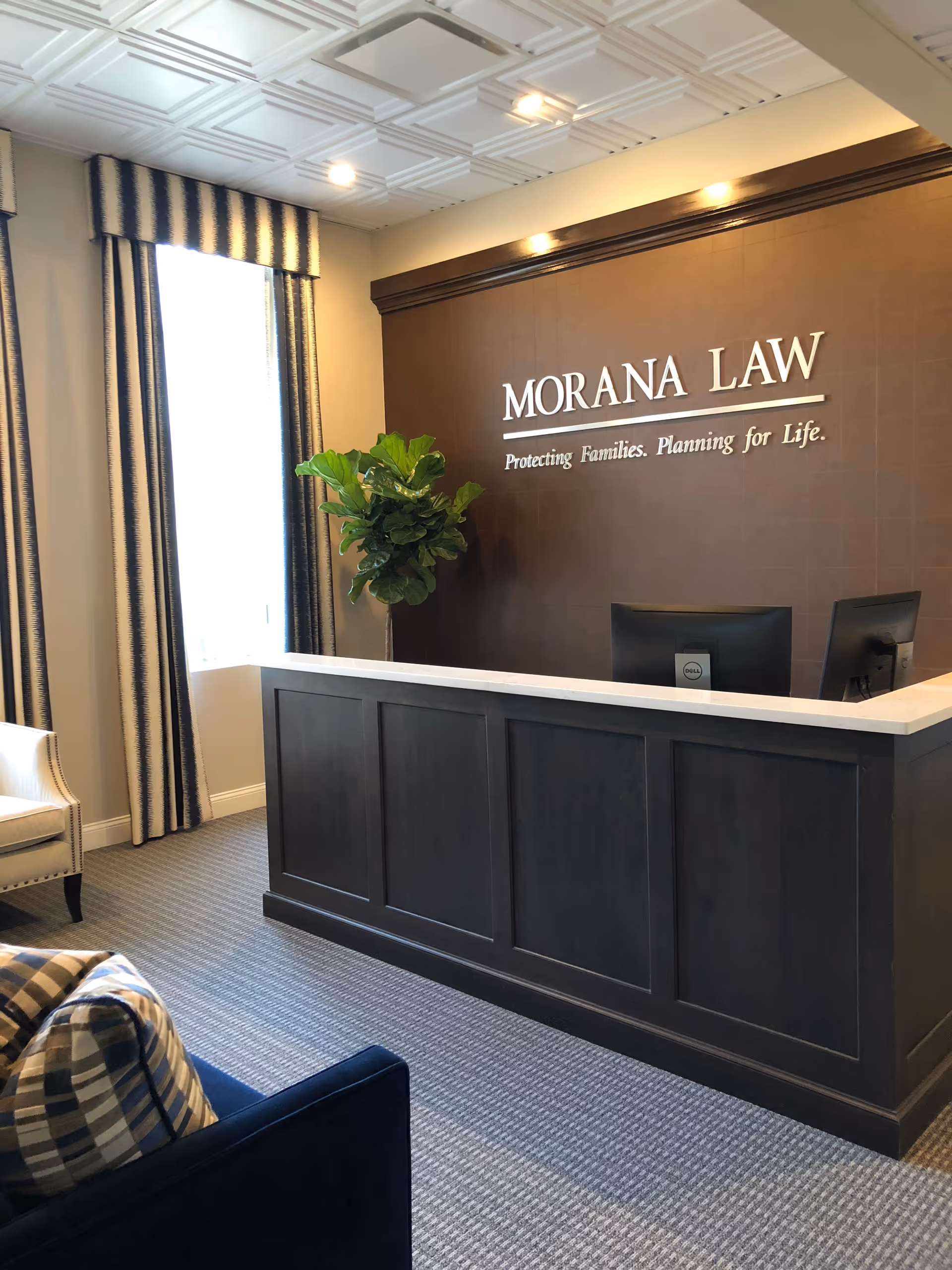 Reception desk in a lobby with a Morana Law Office sign and plant.