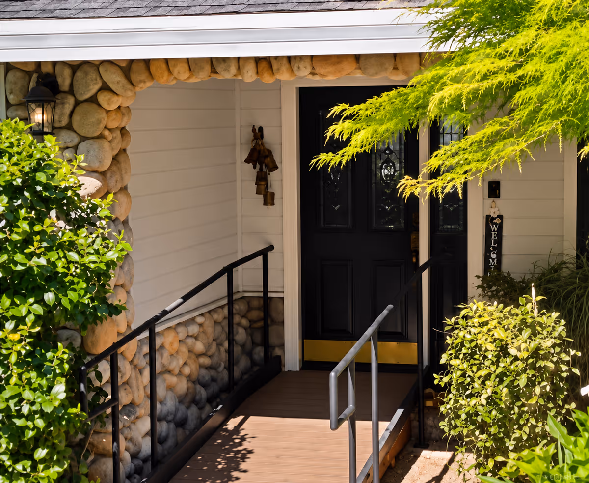 Front entrance of a stone-faced building with a black door and greenery.