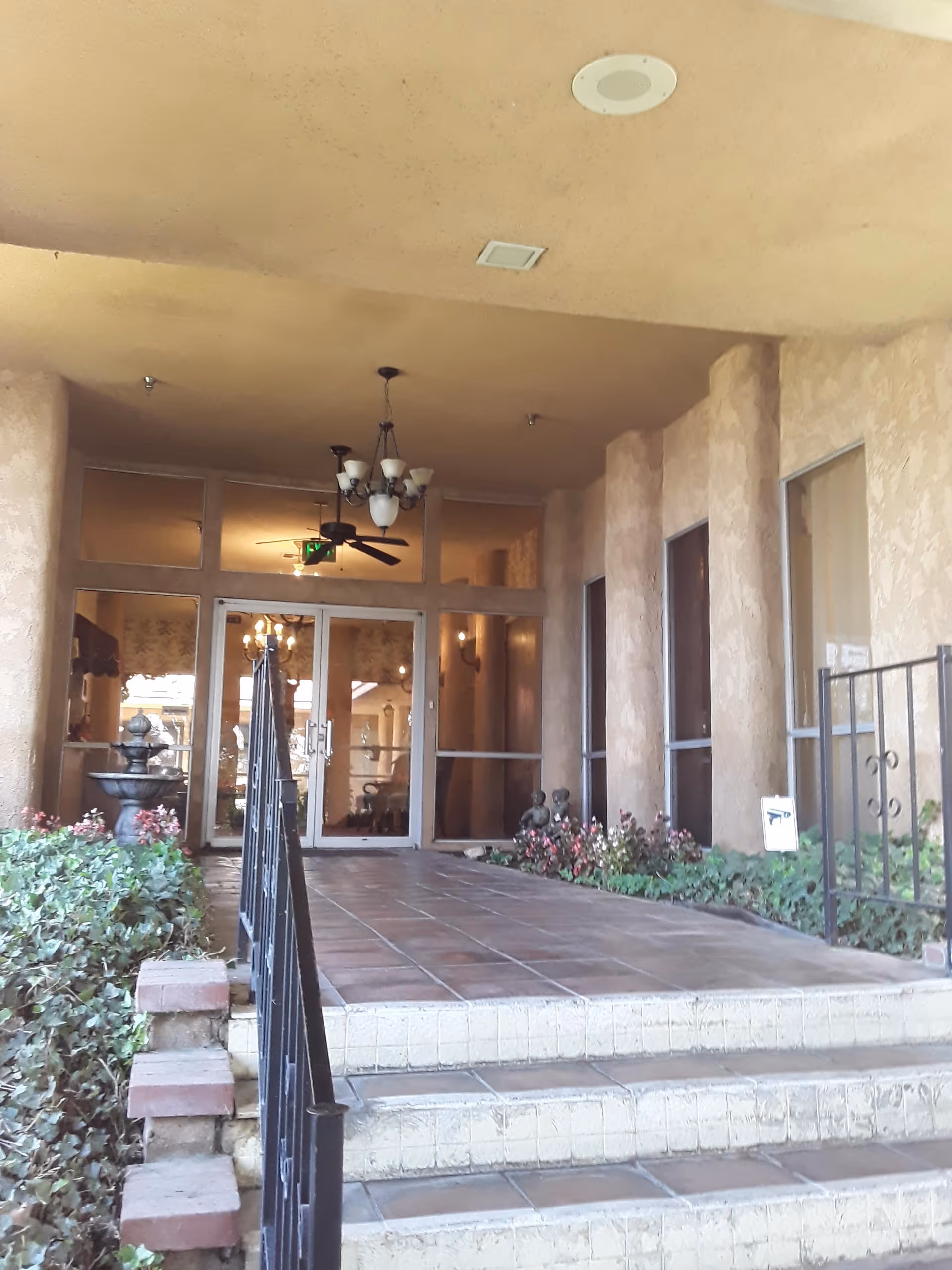 Front entrance of Braswell's Mediterranean Gardens senior living facility with tiled steps and glass doors