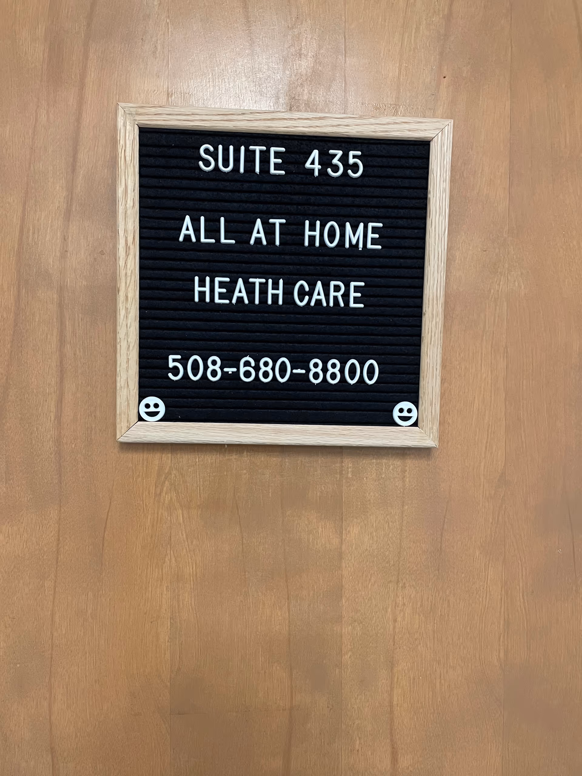 Wooden door with framed sign reading Suite 435 All At Home Health Care 508-680-8800.