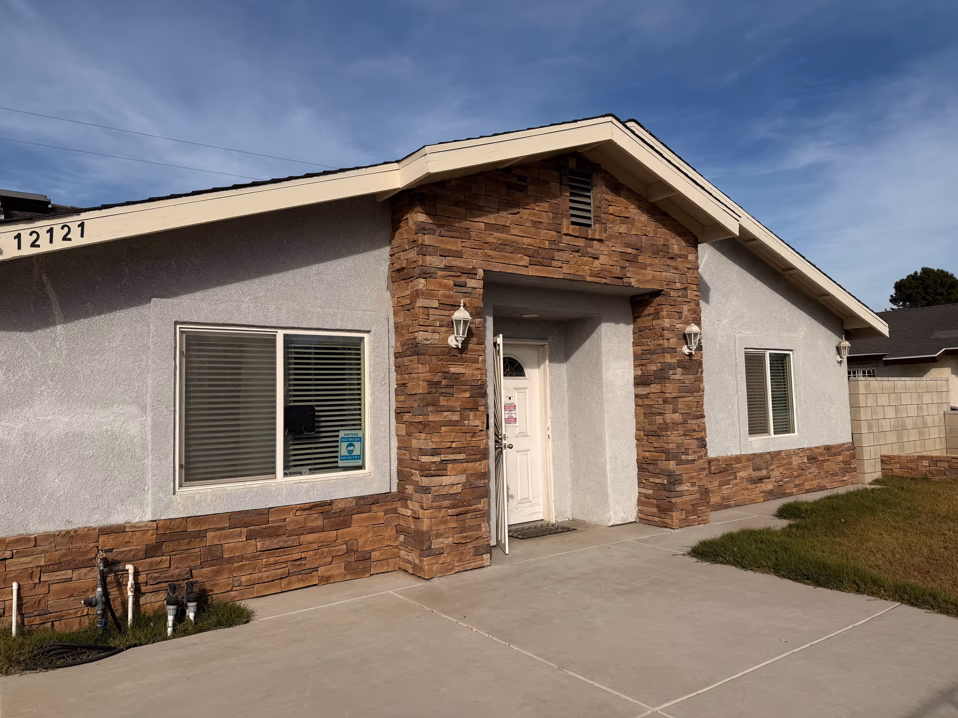 Front view of a single-story building with stone accents and a white entrance door.