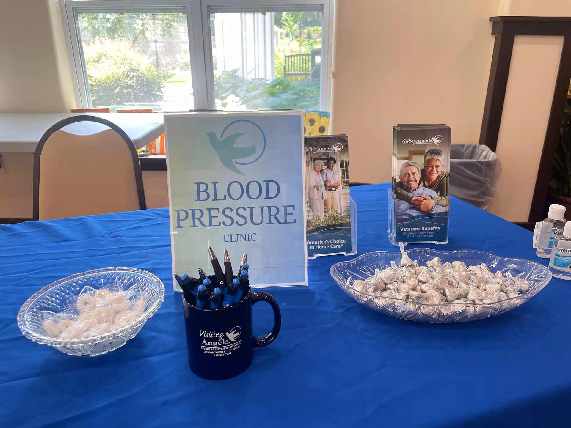 Indoor table with blue cloth, Blood Pressure Clinic sign, pamphlets, and mint bowls.