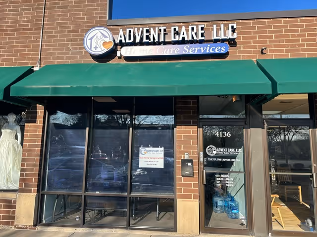 Brick storefront with Advent Care LLC sign and green awning above glass doors.