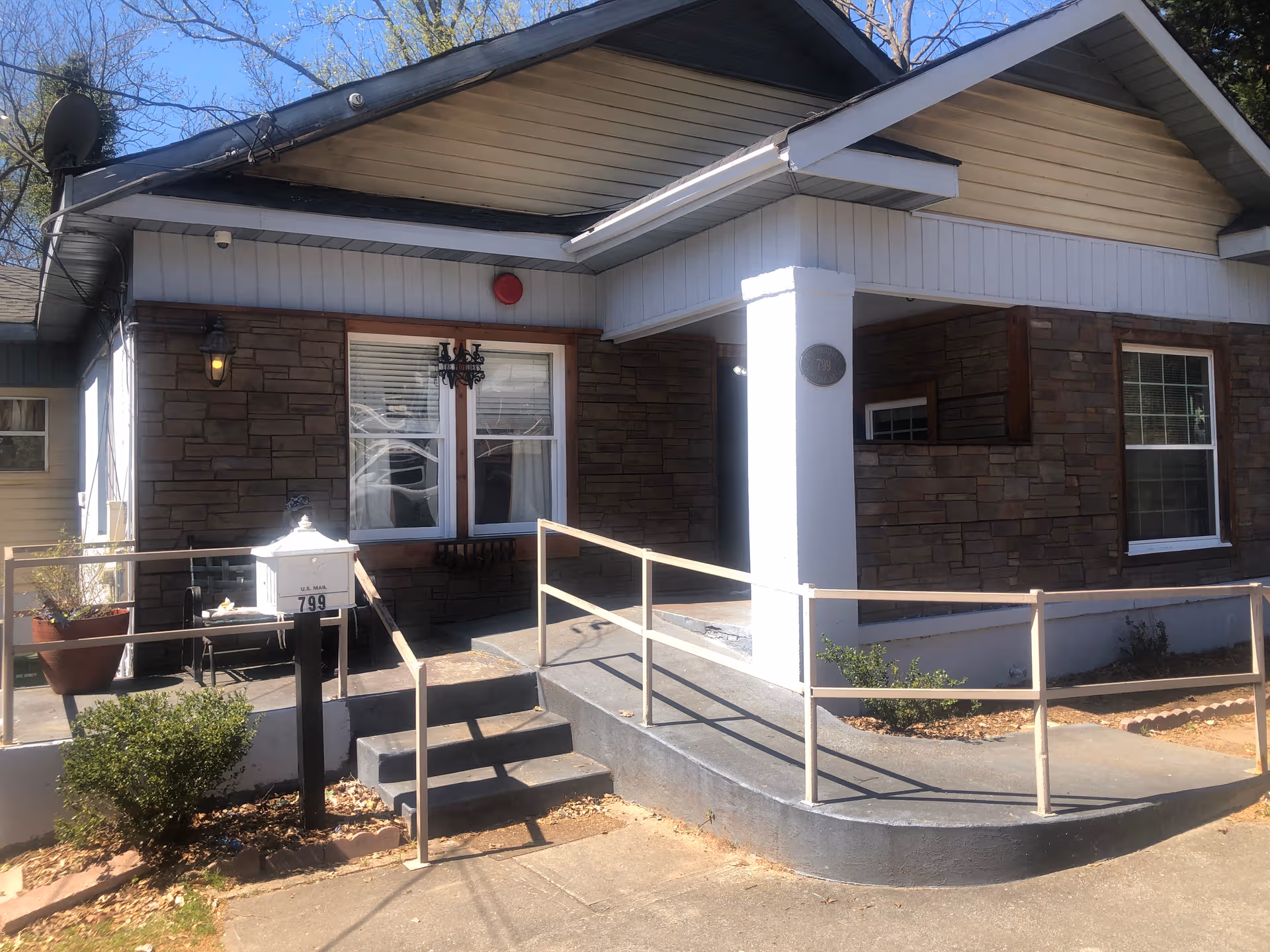 Front exterior of a senior living facility with ramp, stairs, and brick siding.