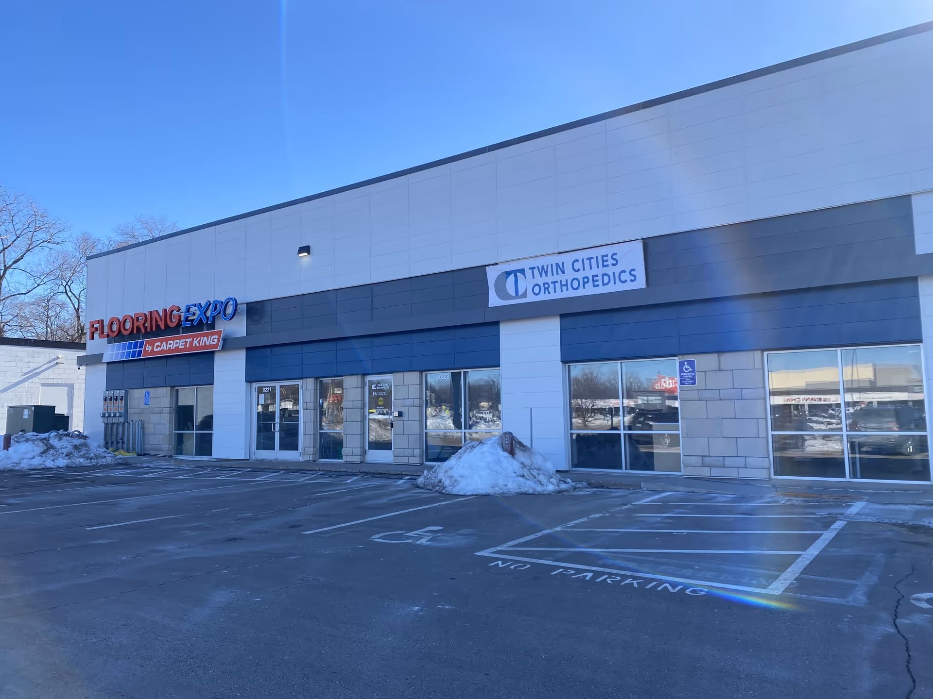 Front exterior of a commercial plaza with Flooring Expo and Twin Cities Orthopedics signage.