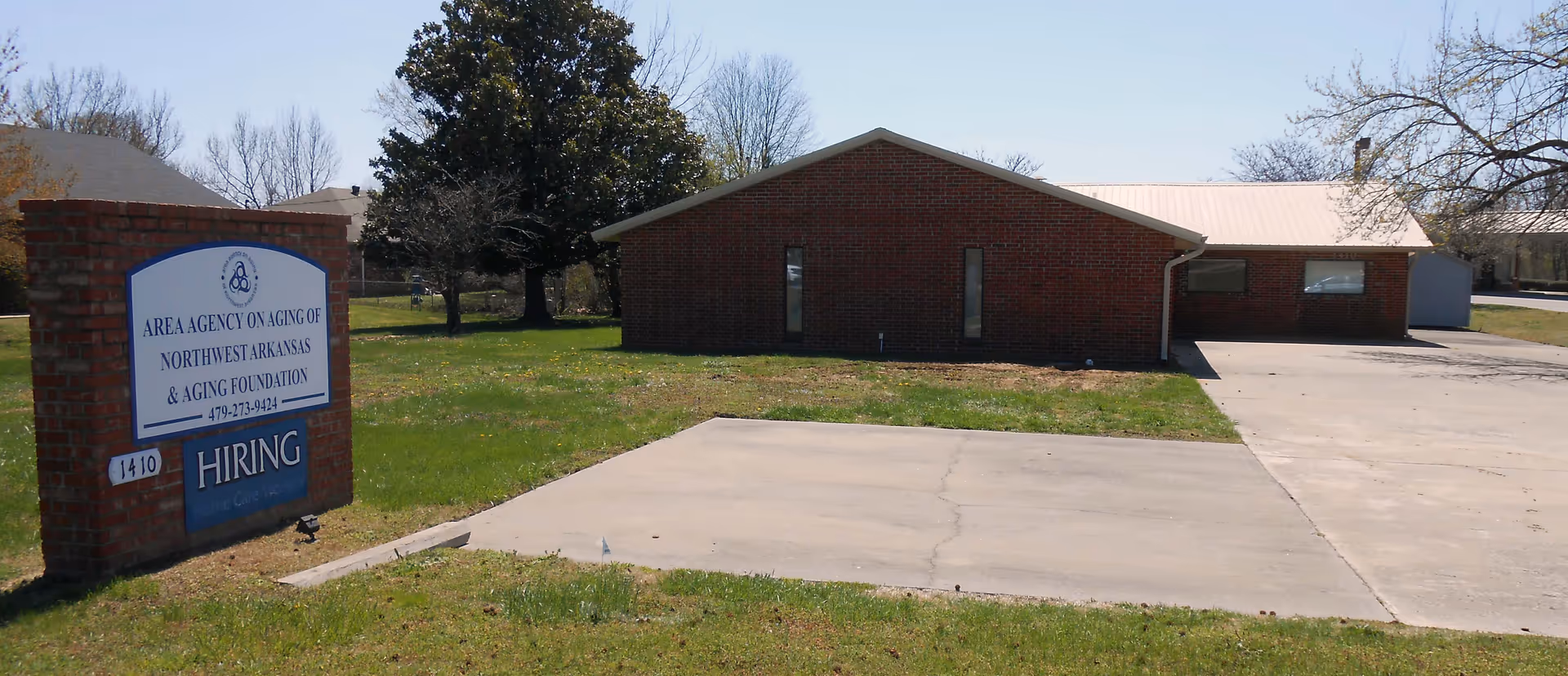 Exterior brick building of Northwest Arkansas Area Agency on Aging, with hiring sign.