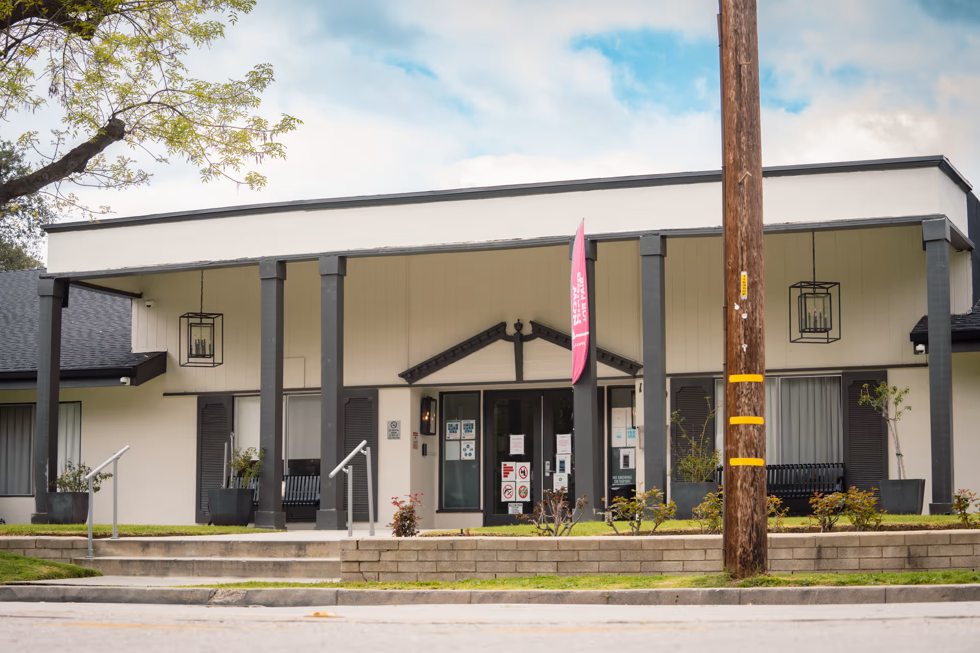 Front view of Rose Garden Healthcare Center with entrance, pillars, and a street in foreground.