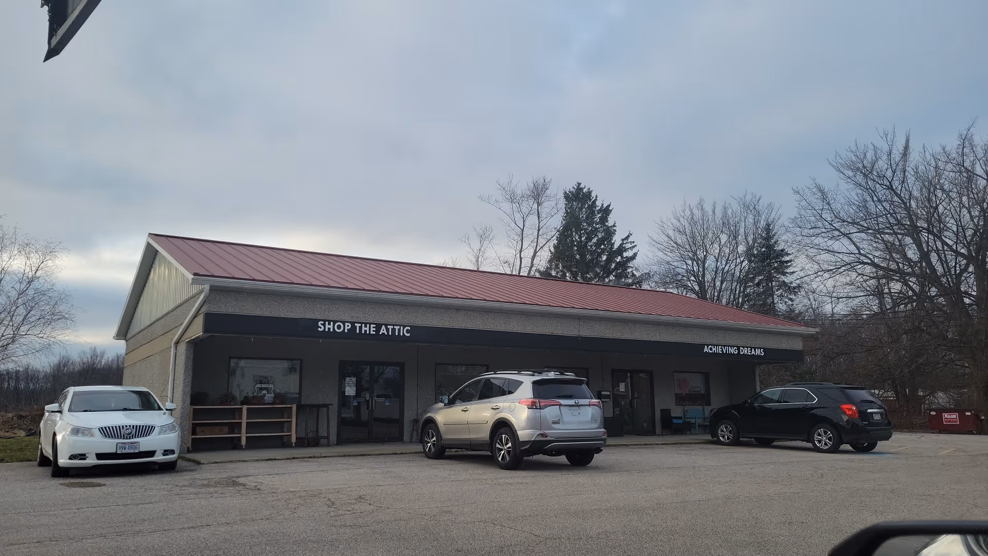 Exterior of a single-story shop with 'Shop the Attic' and 'Achieving Dreams' signs.
