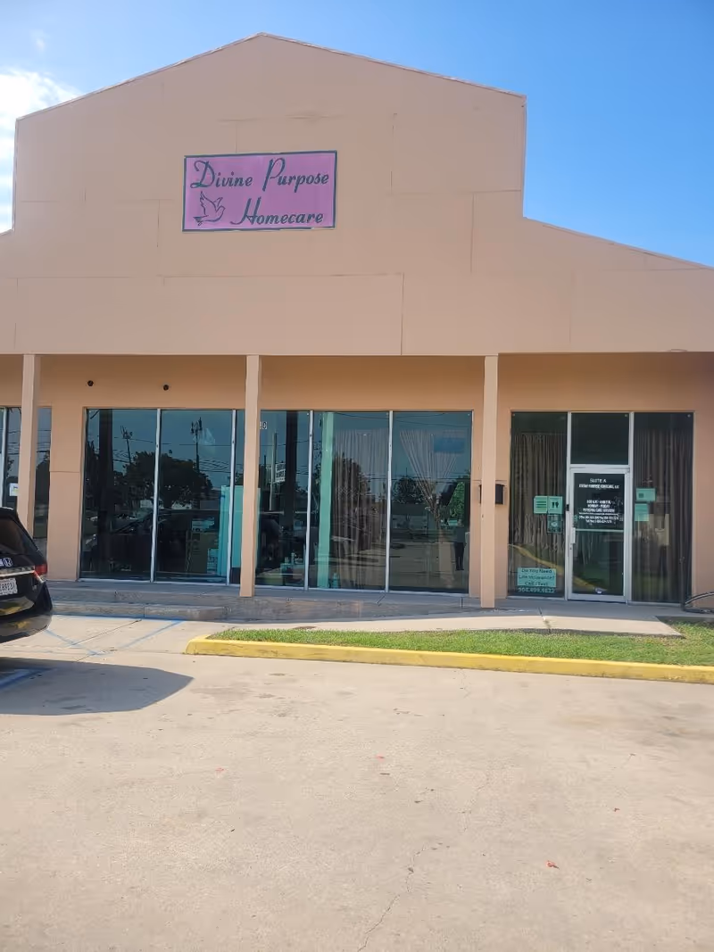Front of a peach-colored building with glass storefronts and a purple sign reading Divine Purpose Homecare.