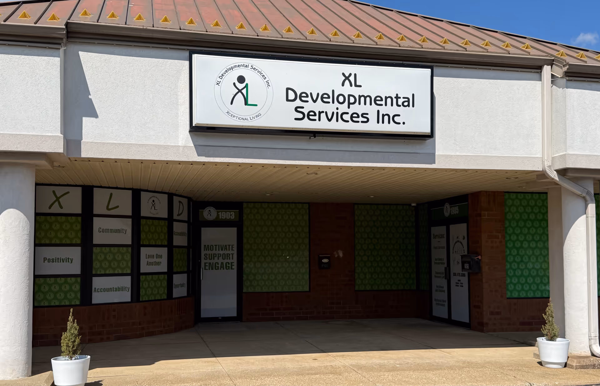 Exterior storefront of XL Developmental Services Inc. with green panels and planters.