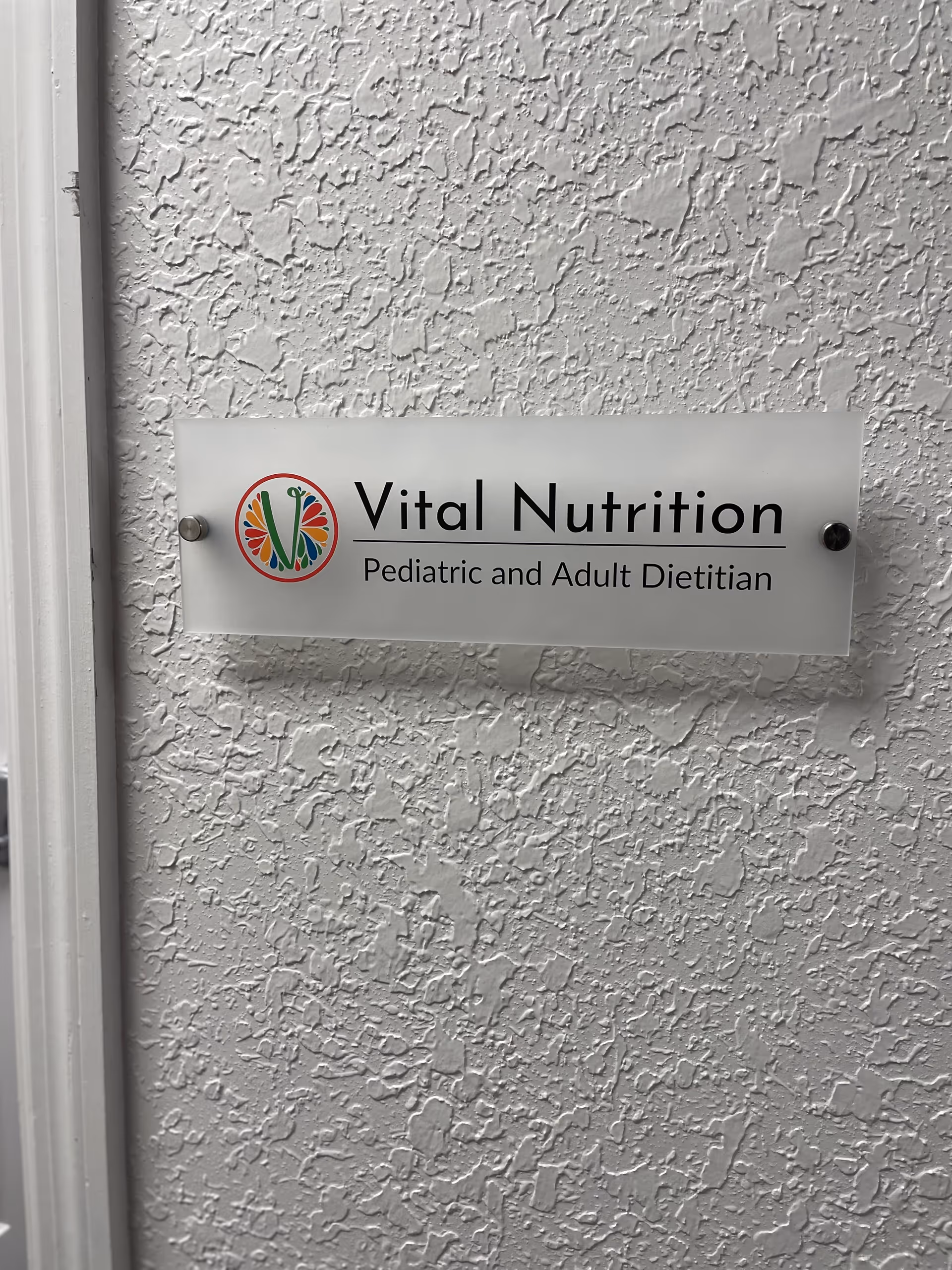 Exterior textured wall with a Vital Nutrition sign and logo.
