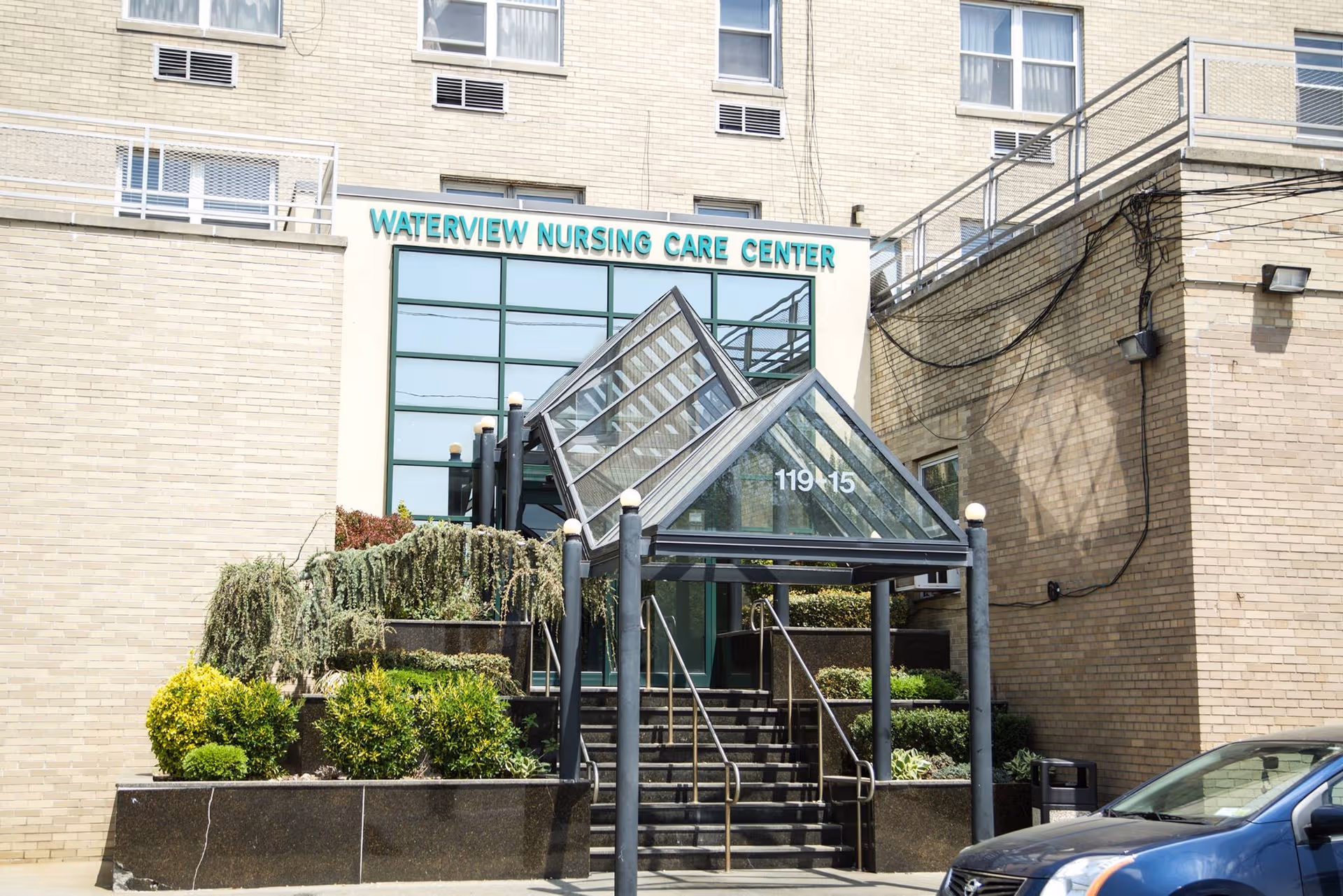 Front view of Waterview Nursing & Rehabilitation Center entrance with glass atrium and stairs.