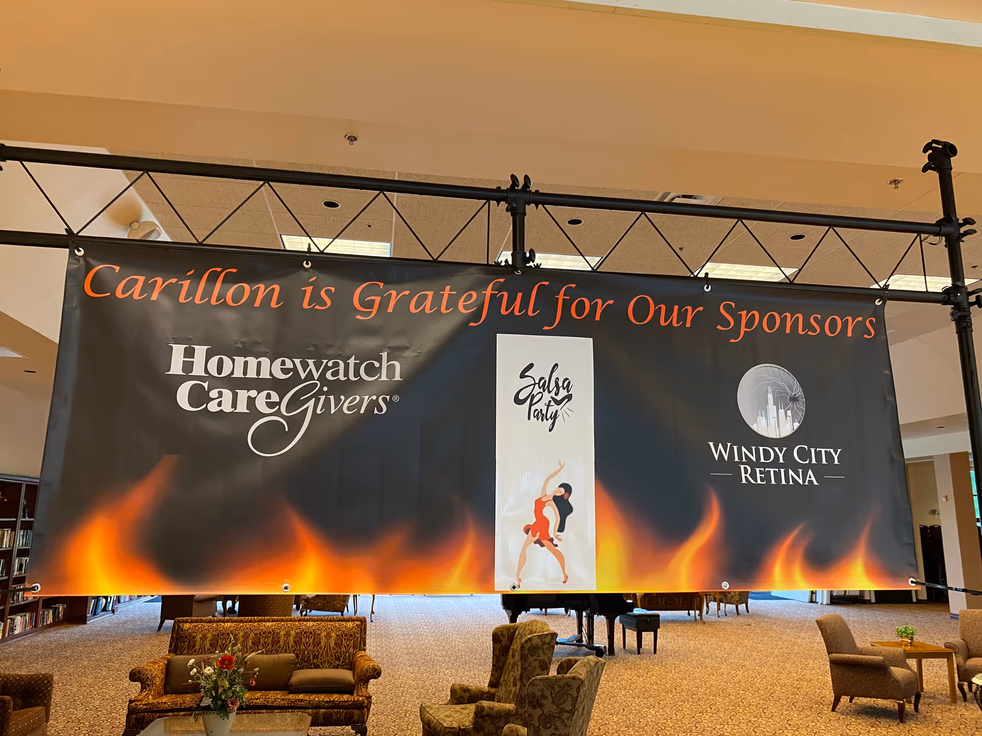 Indoor lobby with a large sponsor banner and seating in a senior living facility.