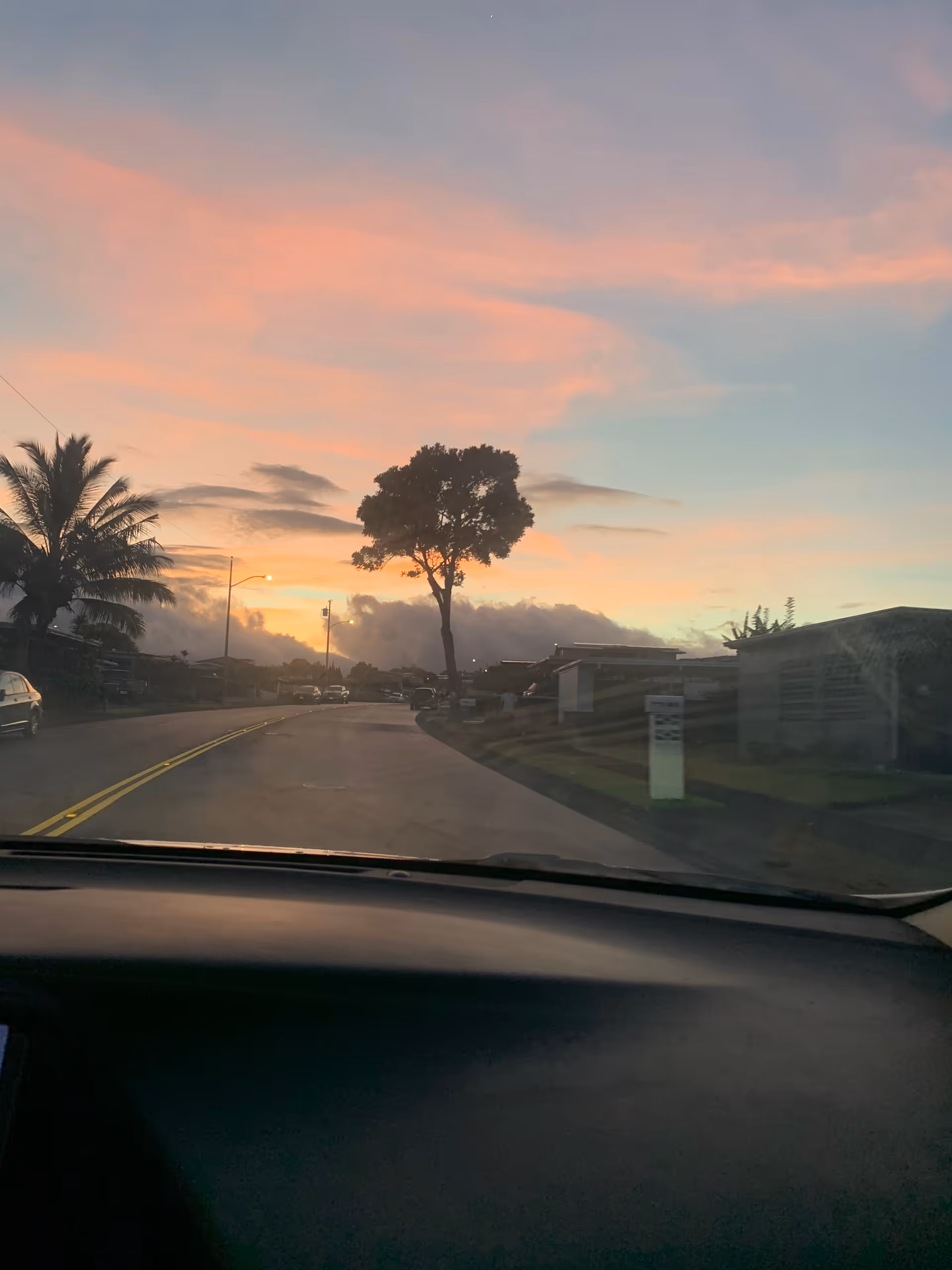 Sunrise over a suburban street seen from inside a car