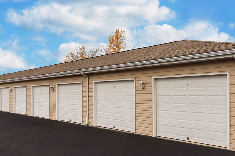 Exterior view of a row of beige garage doors on a single-story building.