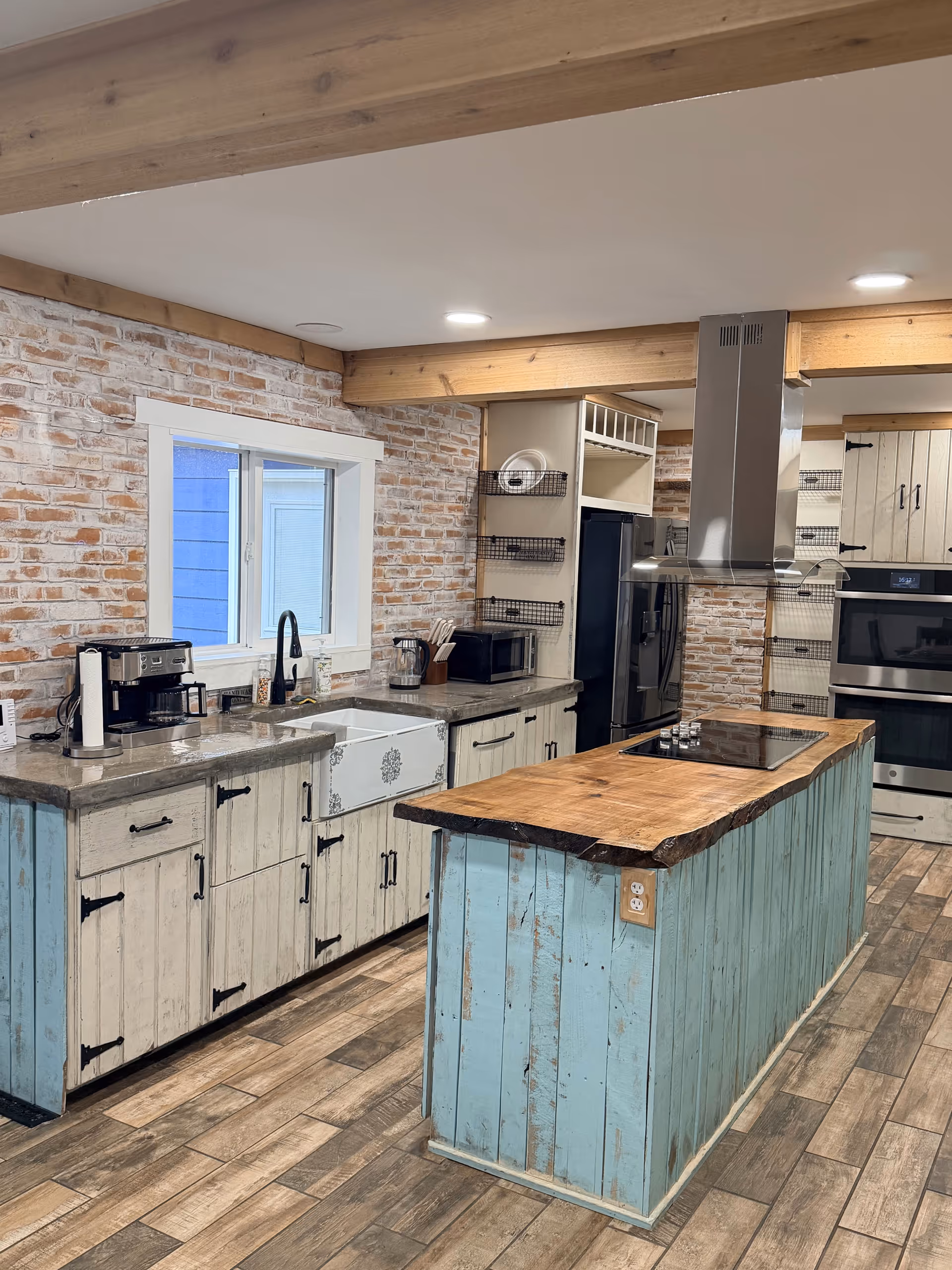 Rustic kitchen with turquoise island, brick walls, and modern stainless appliances.