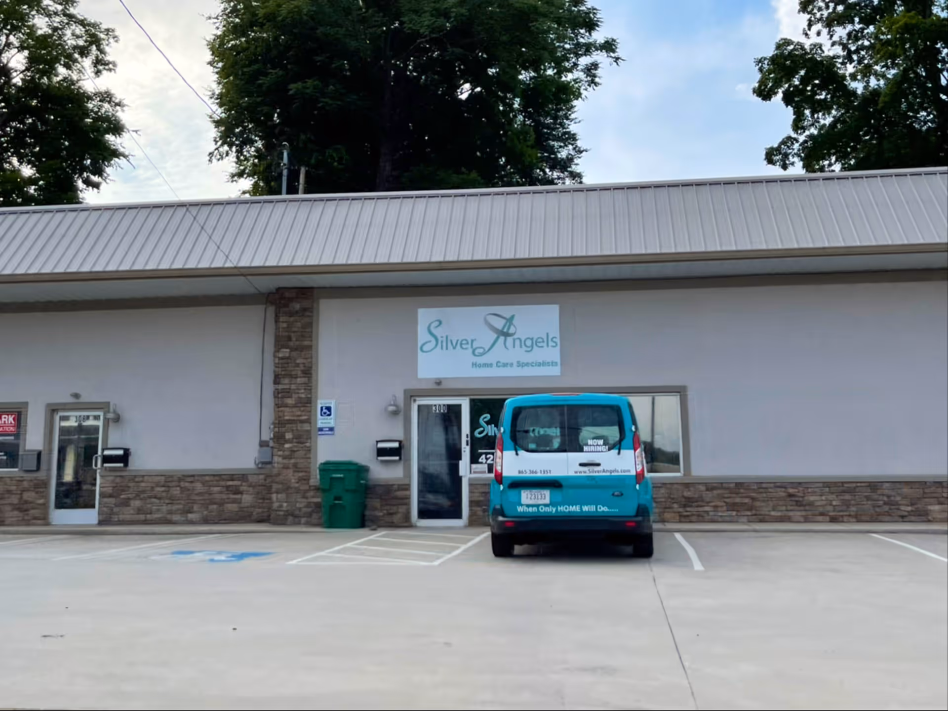 Front of Silver Angels facility with sign, stone facade, and blue van parked outside
