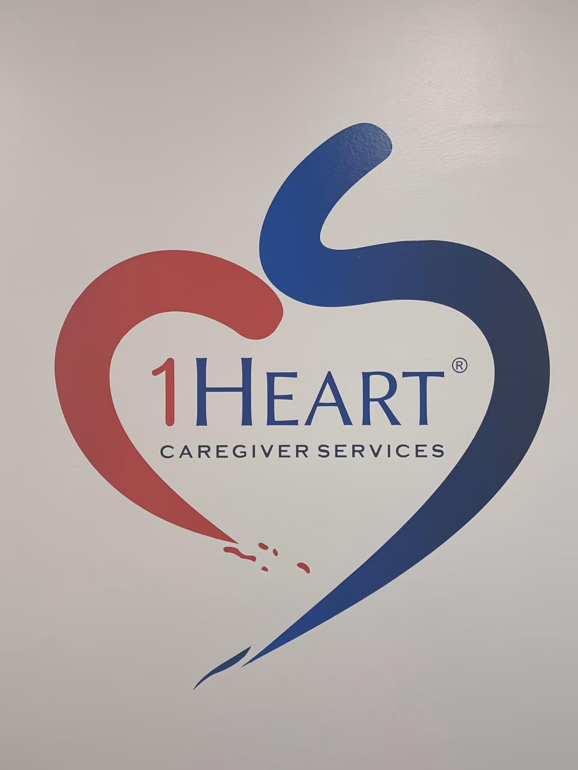 Interior wall featuring a red-and-blue heart logo with 1Heart Caregiver Services text.