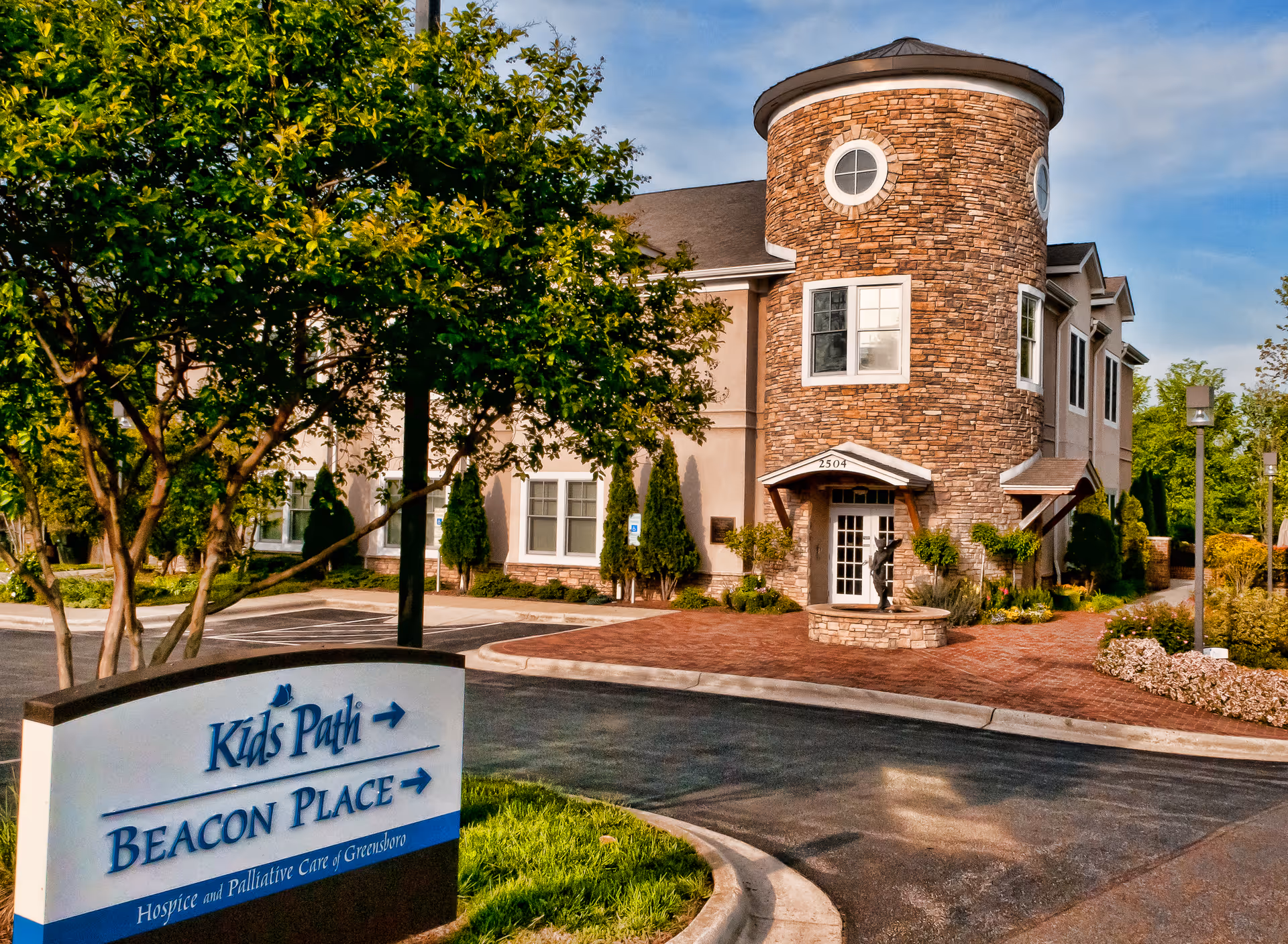 Exterior view of a stone senior living facility with a brick courtyard and welcoming entrance.