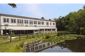Village House Nursing and Rehabilitation Center building with a pond and green grounds.