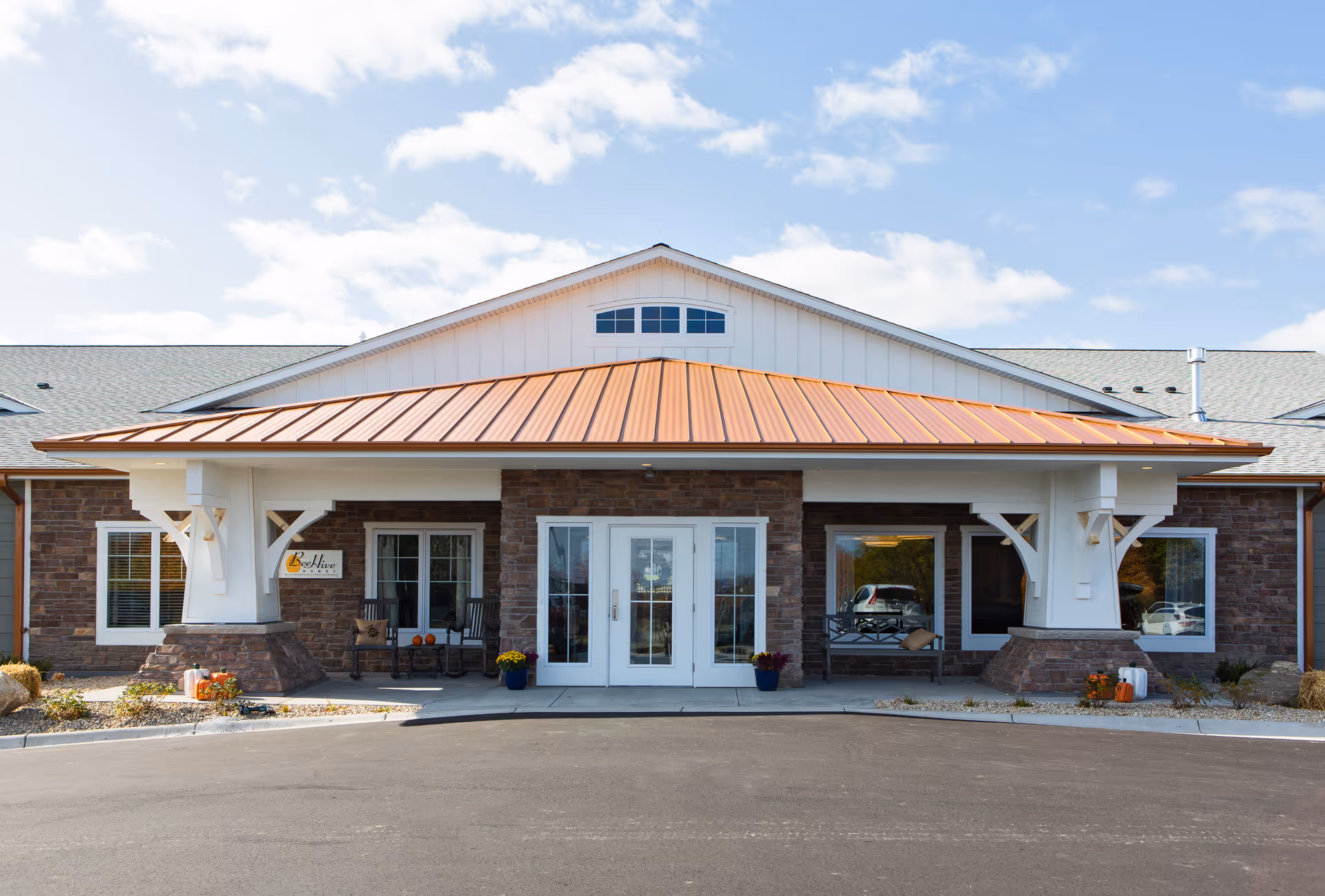 Bee Hive Homes Maple Grove exterior entrance with white columns, brick siding, and glass doors.