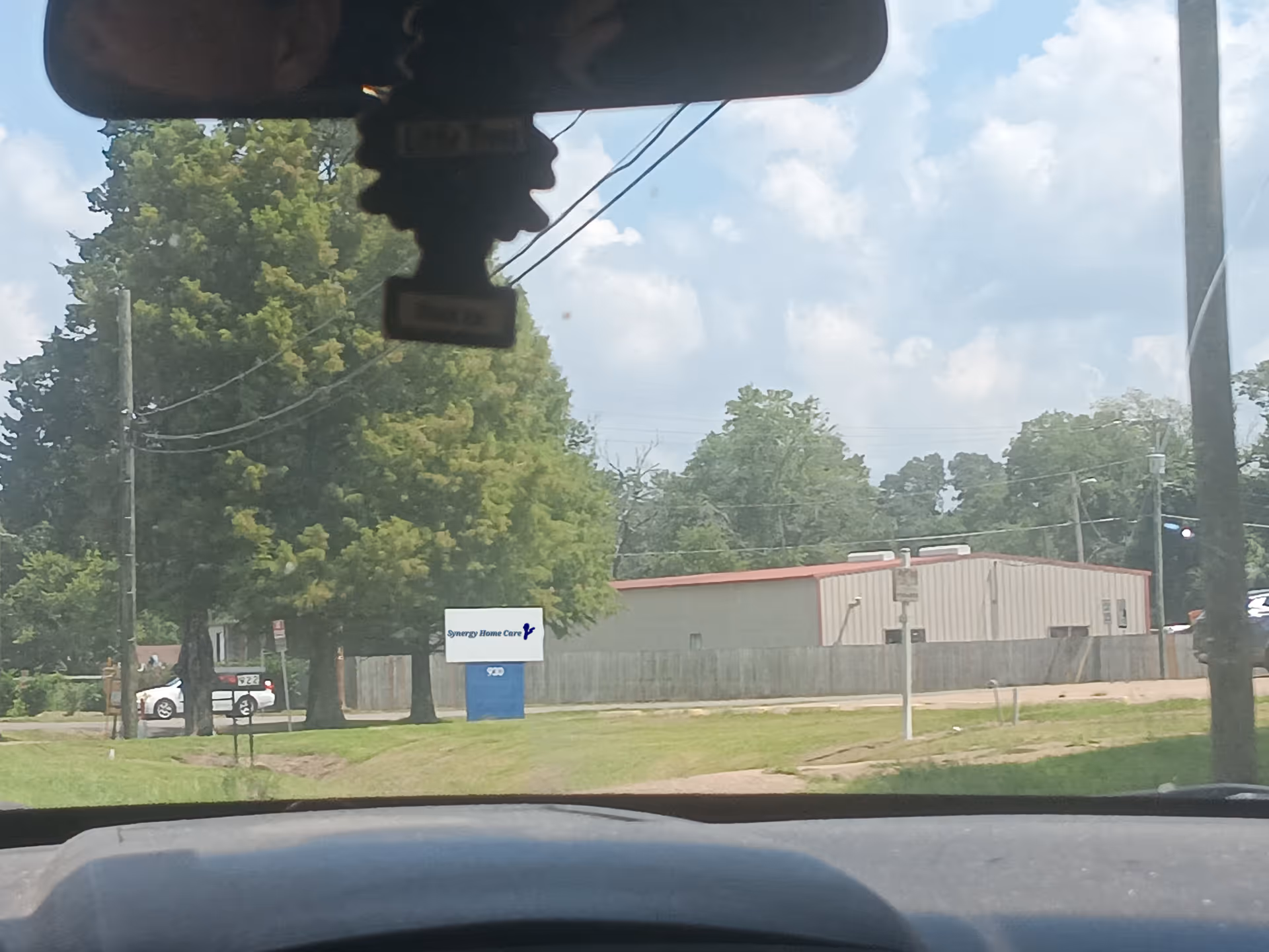 View from inside a car of a care facility exterior with a sign near the street.