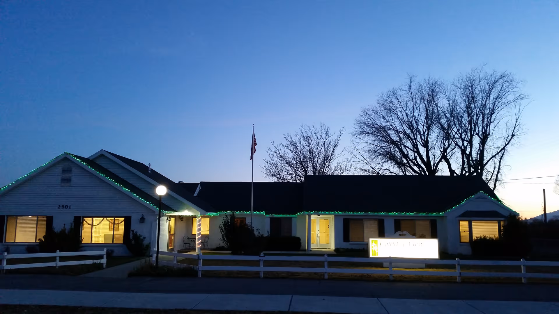 Front view of a Country View Assisted Living building at dusk with green roofline lights.