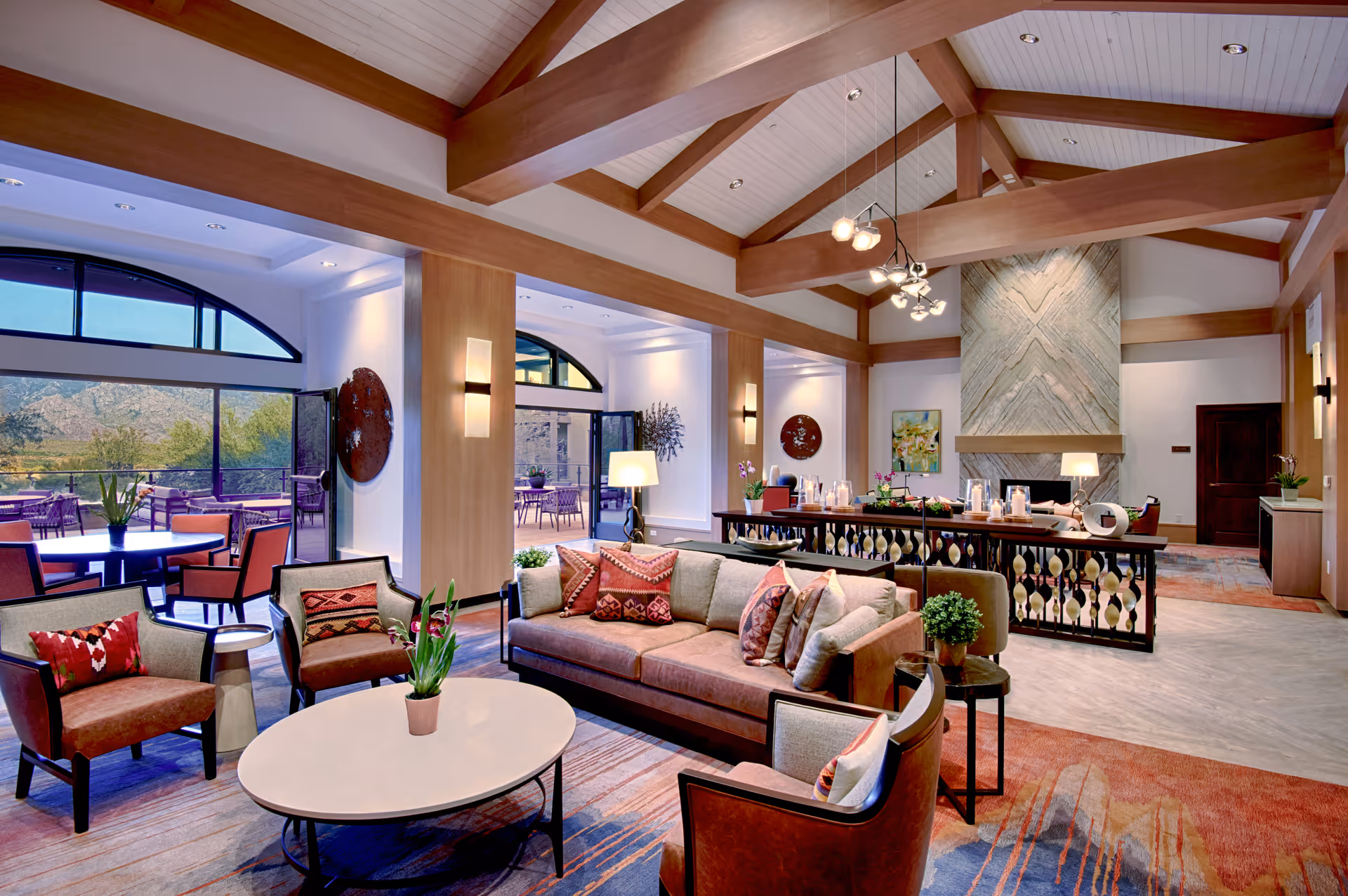 Spacious lounge-style living room with sofas, chairs, and a high-beamed ceiling in warm tones.