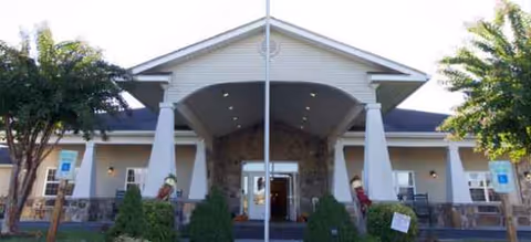 Front entrance of Brookdale Sevierville with stone facade, columns, and trees.
