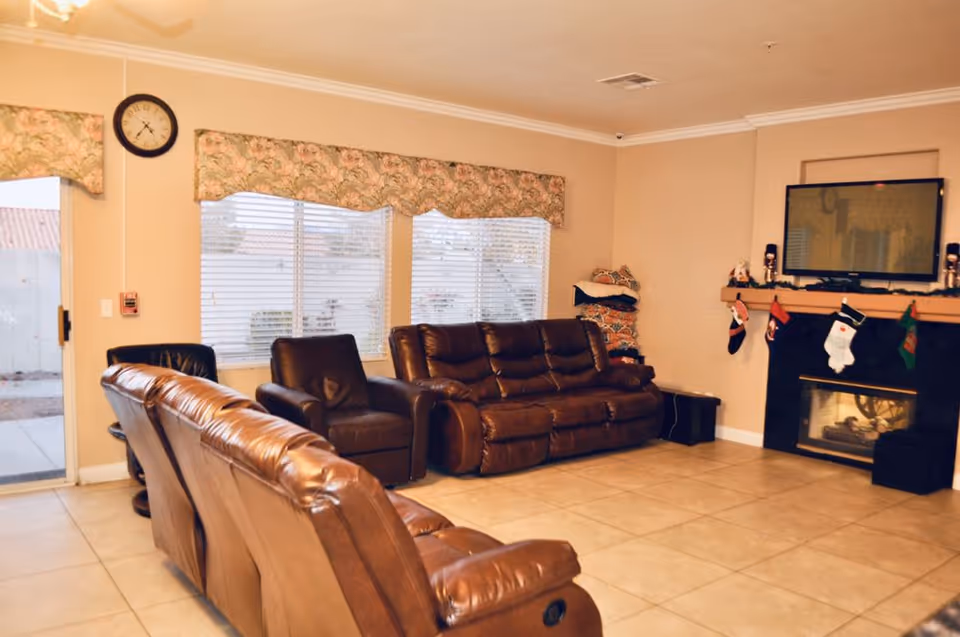 Cozy common living room with leather seating, fireplace, TV, and large windows.
