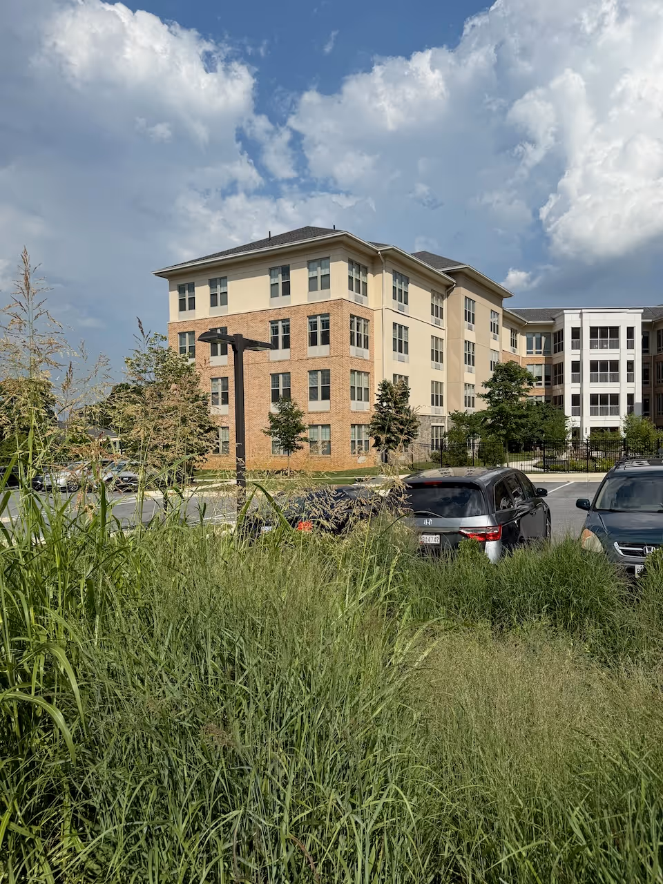 Front view of Charlestown Community senior living building with parked cars and tall grasses.